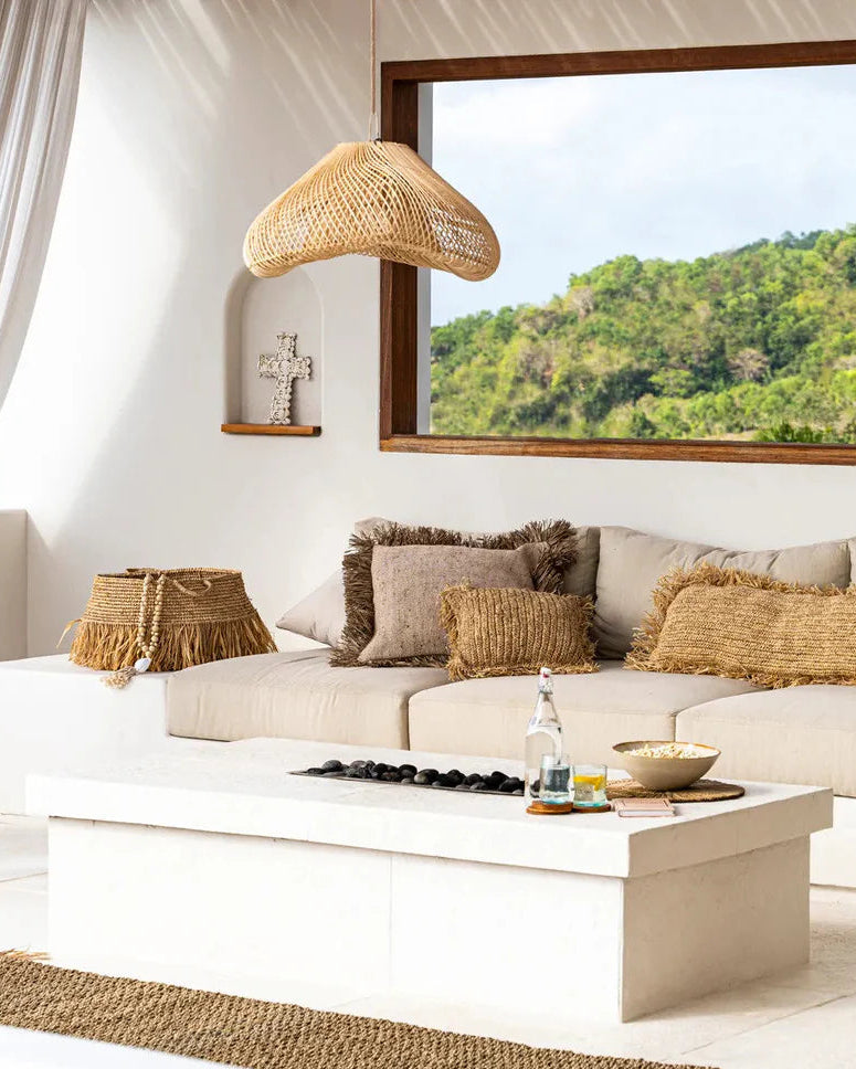 Modern living room with a white sofa, wooden armchair, and large windows overlooking greenery.