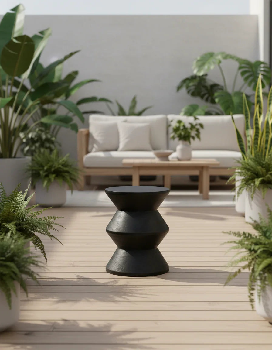 Handcrafted black wooden stool on patio with modern outdoor sofa and lush green plants, Kayu Living