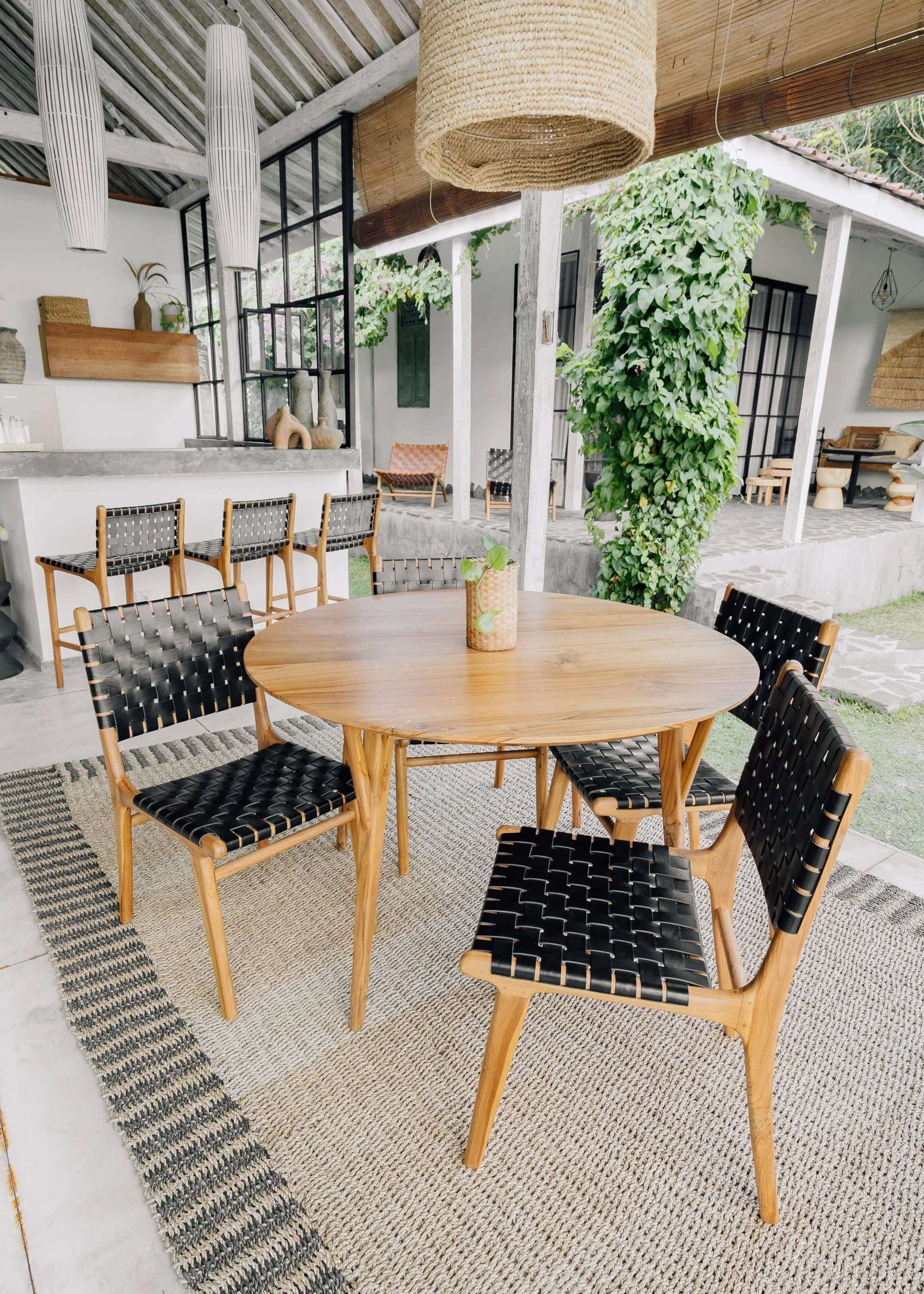 Handmade wooden dining set with black woven chairs in bright, modern Kayu Living outdoor space