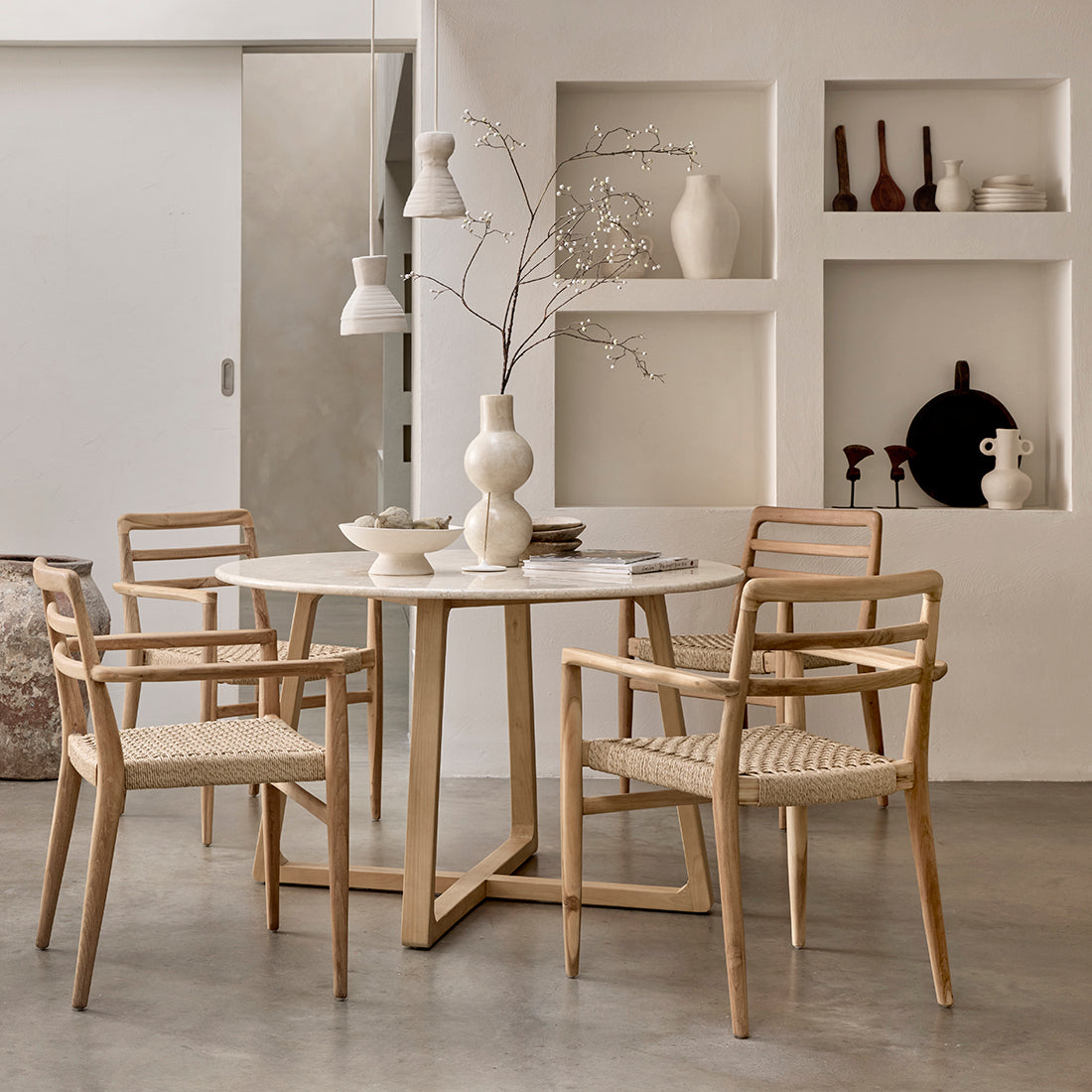 Set of two Raw Materials Verano teak dining chairs with armrests, featuring natural wood finish and modern design.