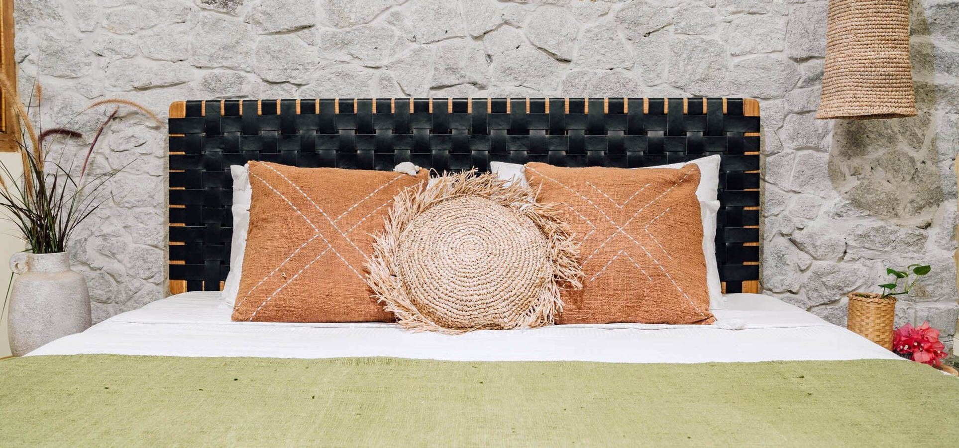 Bed with decorative pillows against a stone wall
