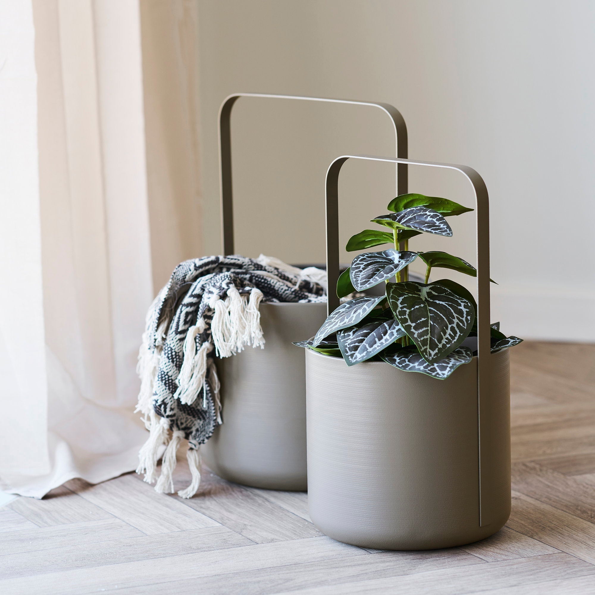 Kayu Living Adana brown plaid recycled cotton throw blanket draped over a modern taupe metal handled planter