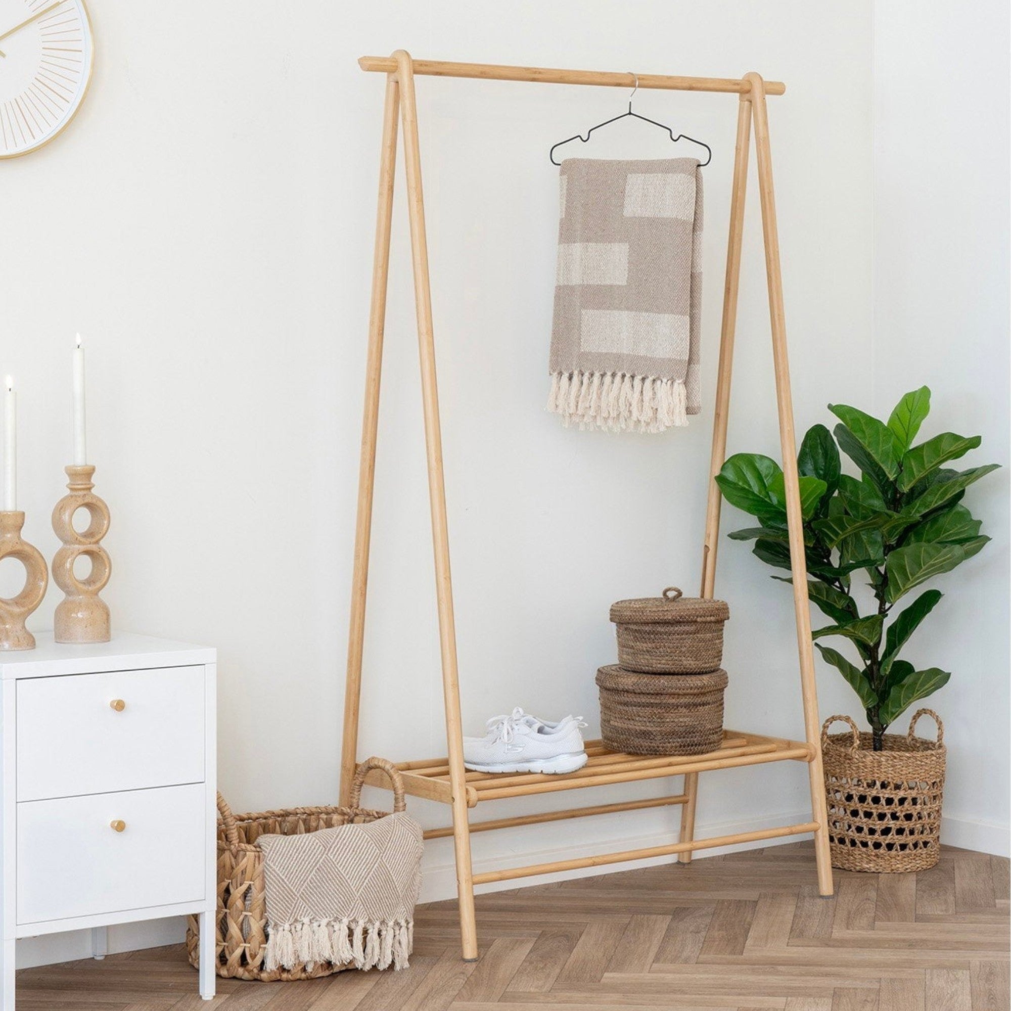 Kayu Living natural bamboo clothes rack with shelf, holding a blanket and shoes. Eco-friendly entryway organizer.