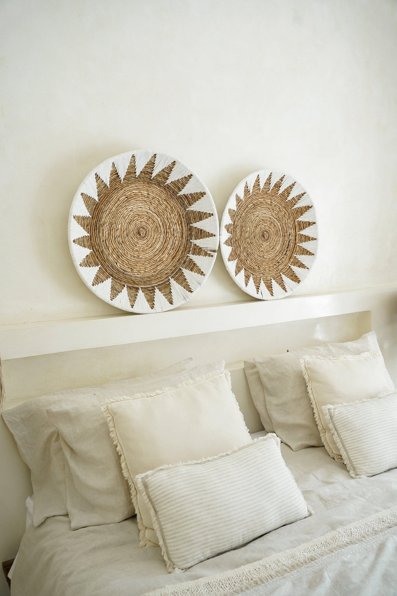 Kayu Living handcrafted bamboo star wall plates in white and brown displayed above a neutral bohemian bedroom bed