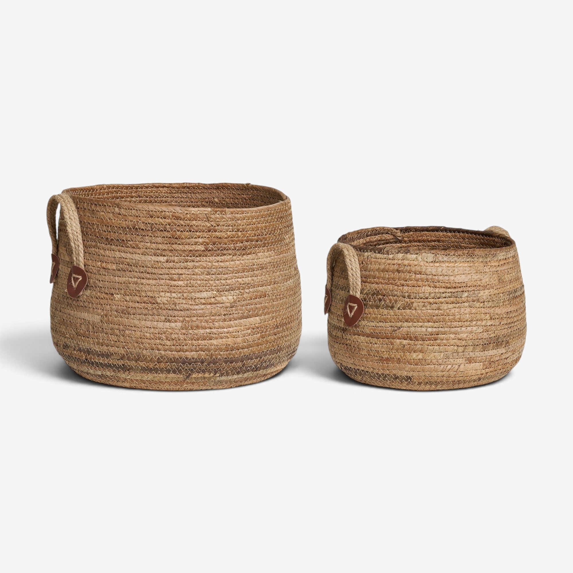 Kayu Living set of two handcrafted natural banana-leaf storage baskets with rope handles and leather accents.