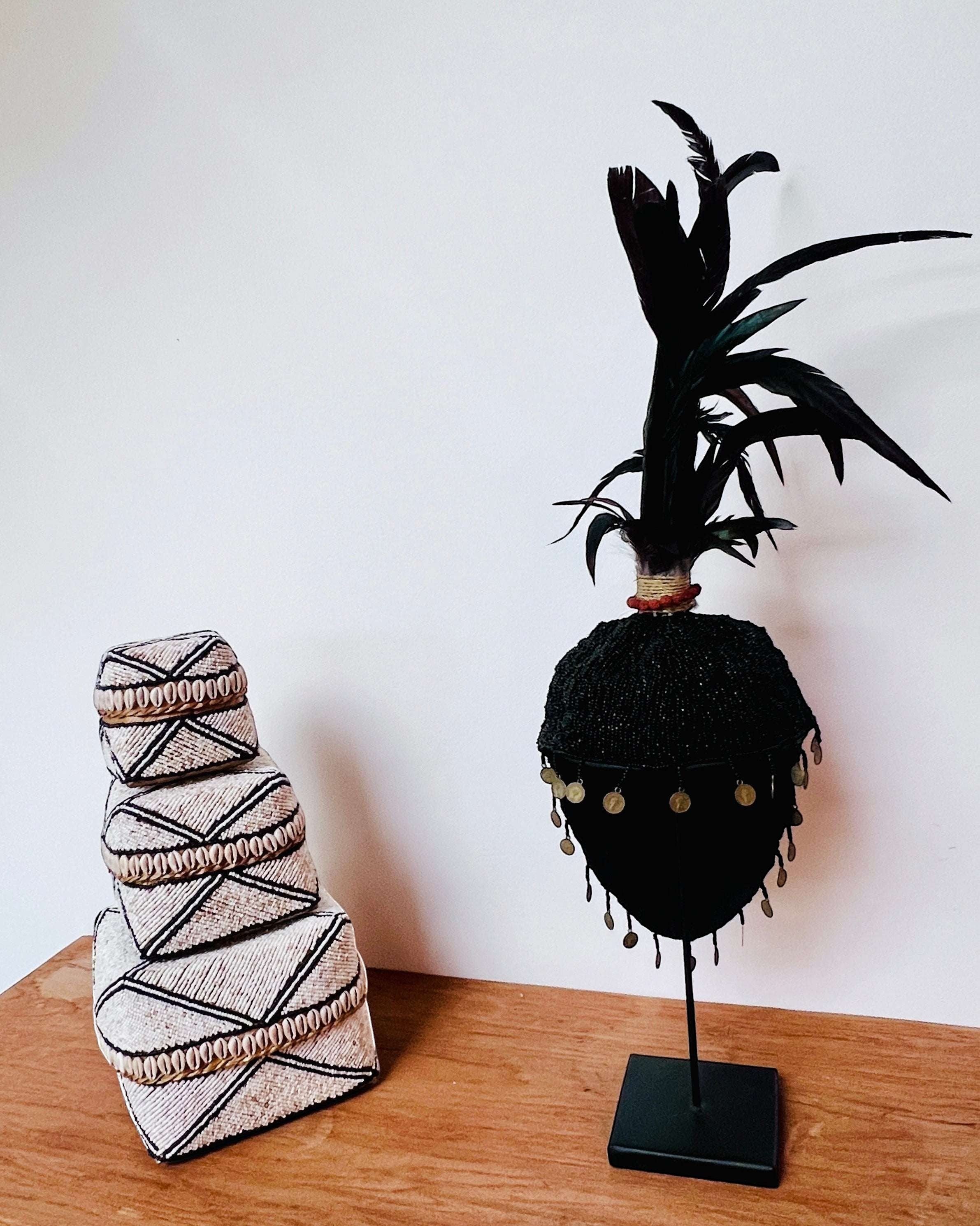 Kayu Living black beaded hat decoration with feathers and coins on a stand, handmade art piece.