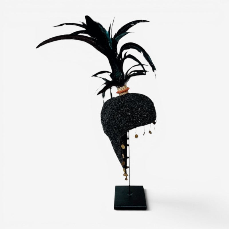 Kayu Living black beaded hat with feathers and gold accents on a stand, a unique decorative art piece.