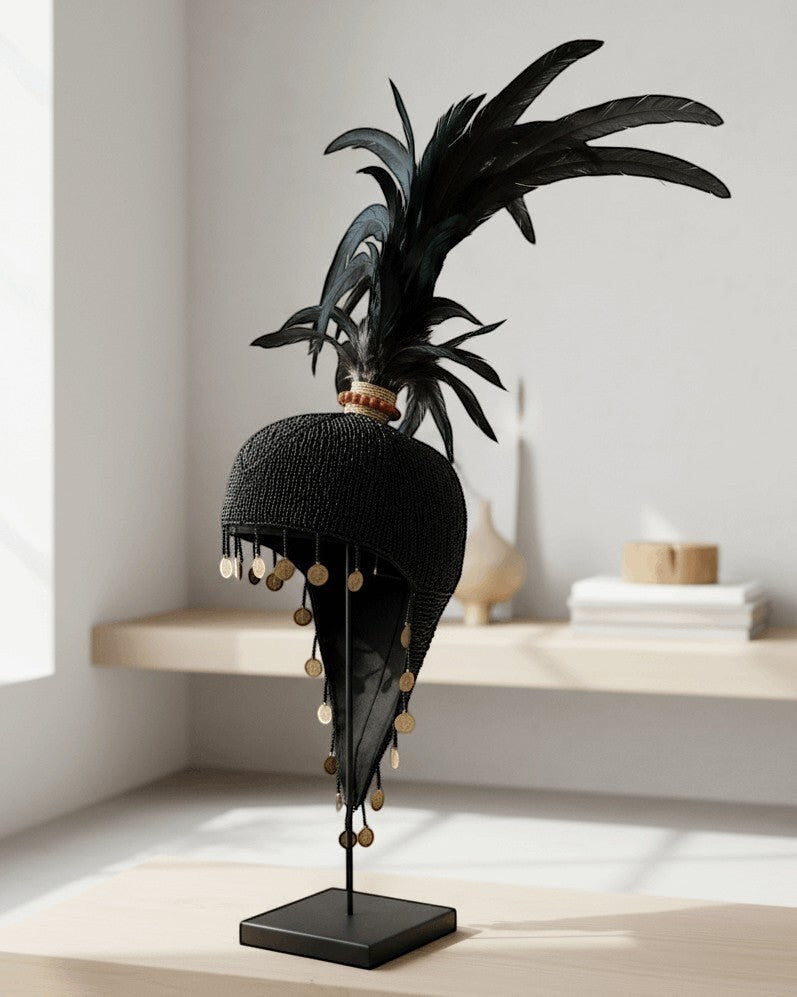 Kayu Living black beaded hat decoration with feathers and gold coins on a stand.