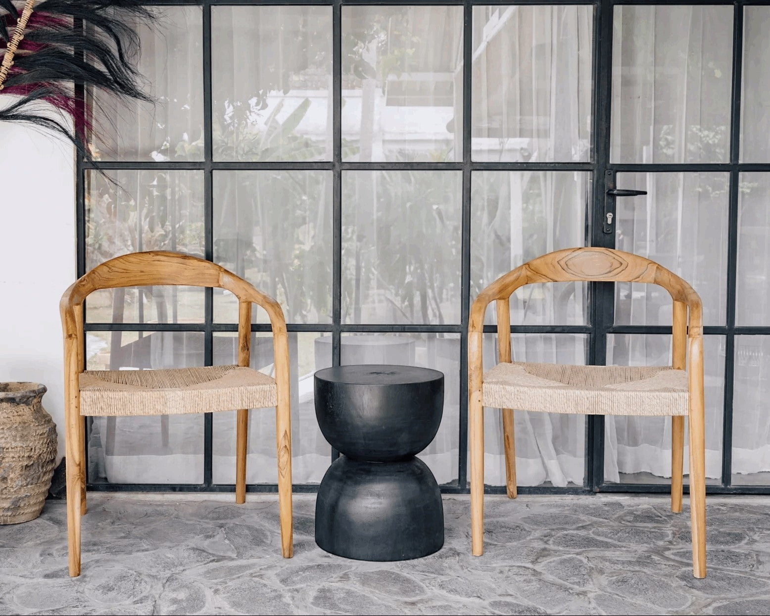 Kayu Living black hourglass stool made from solid suar wood with natural grain, handmade by artisans in Java.