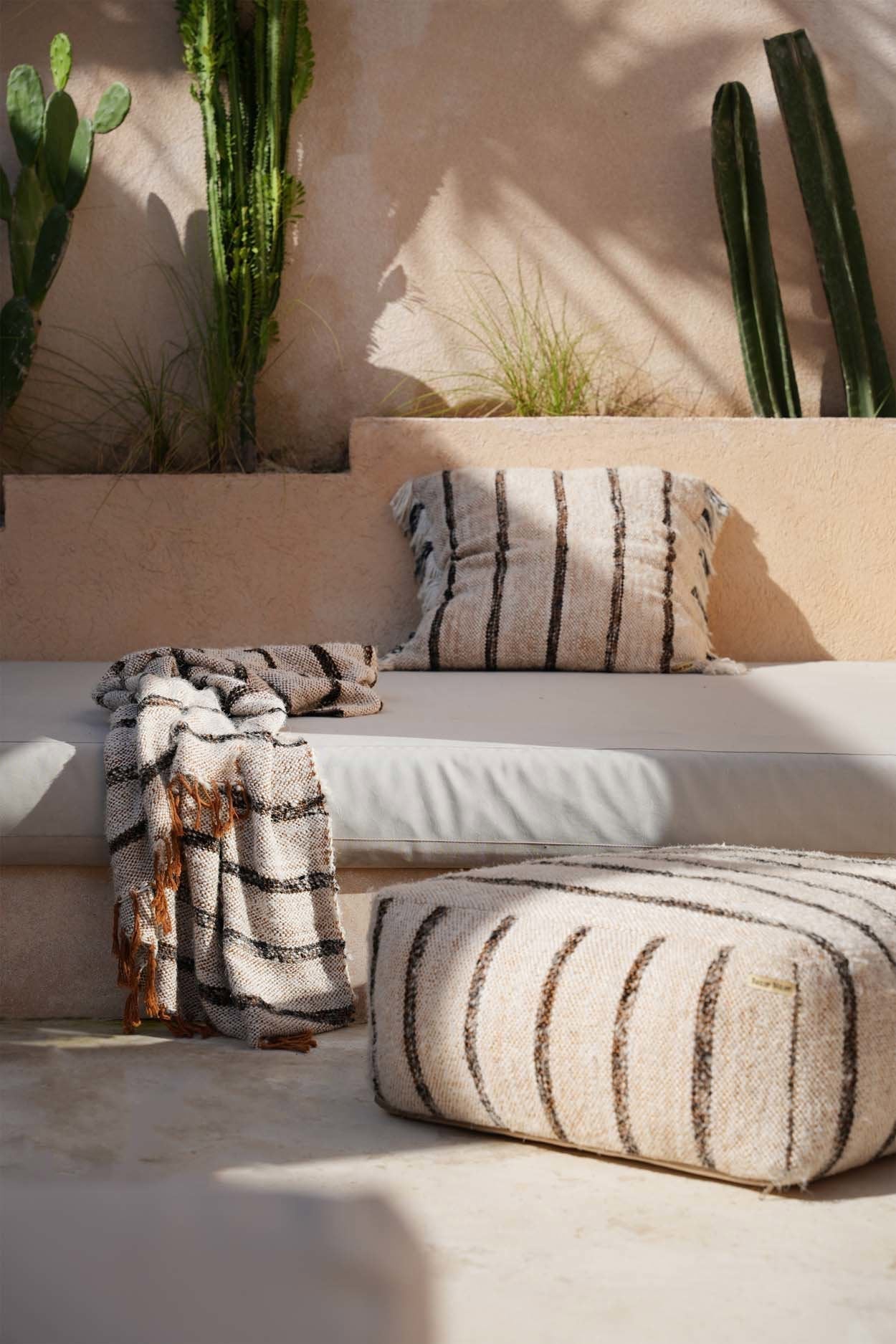 Kayu Living hand-woven Bohemian White cotton throw with fringed edges and dark striped texture on a patio sofa