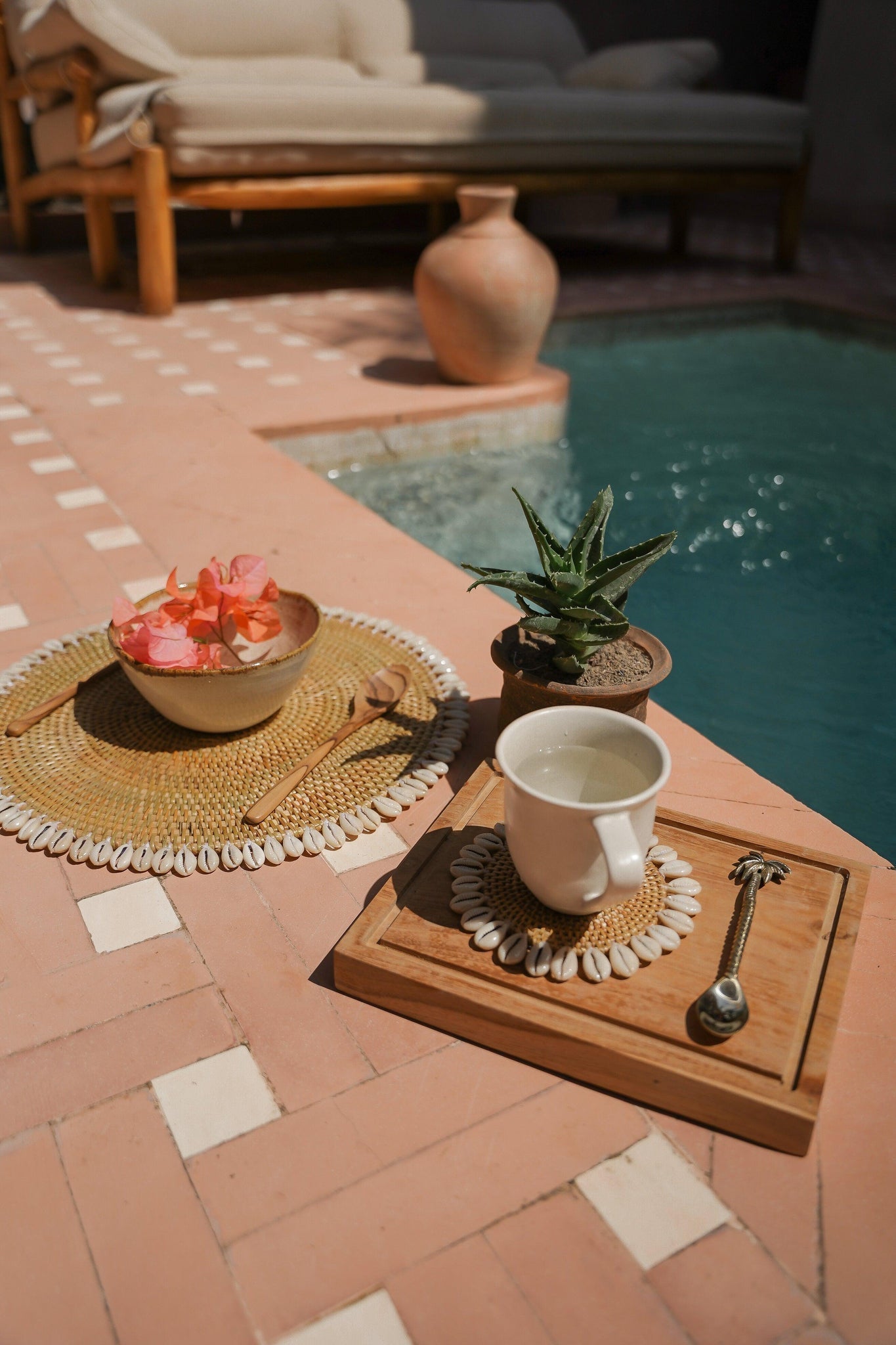 Kayu Living handcrafted brass palm tree spoon resting on a wooden board by a pool, featuring a bohemian design.