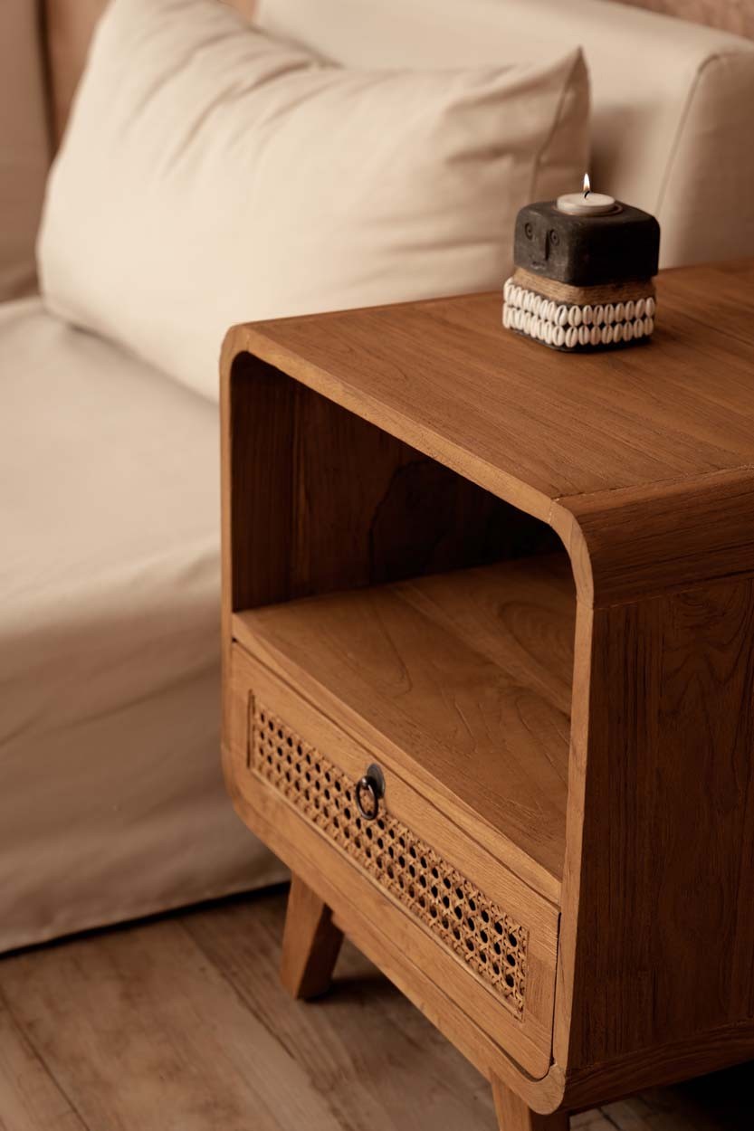 Kayu Living The Breeze nightstand in teak wood with a handwoven rattan drawer and open shelf in a bedroom setting.