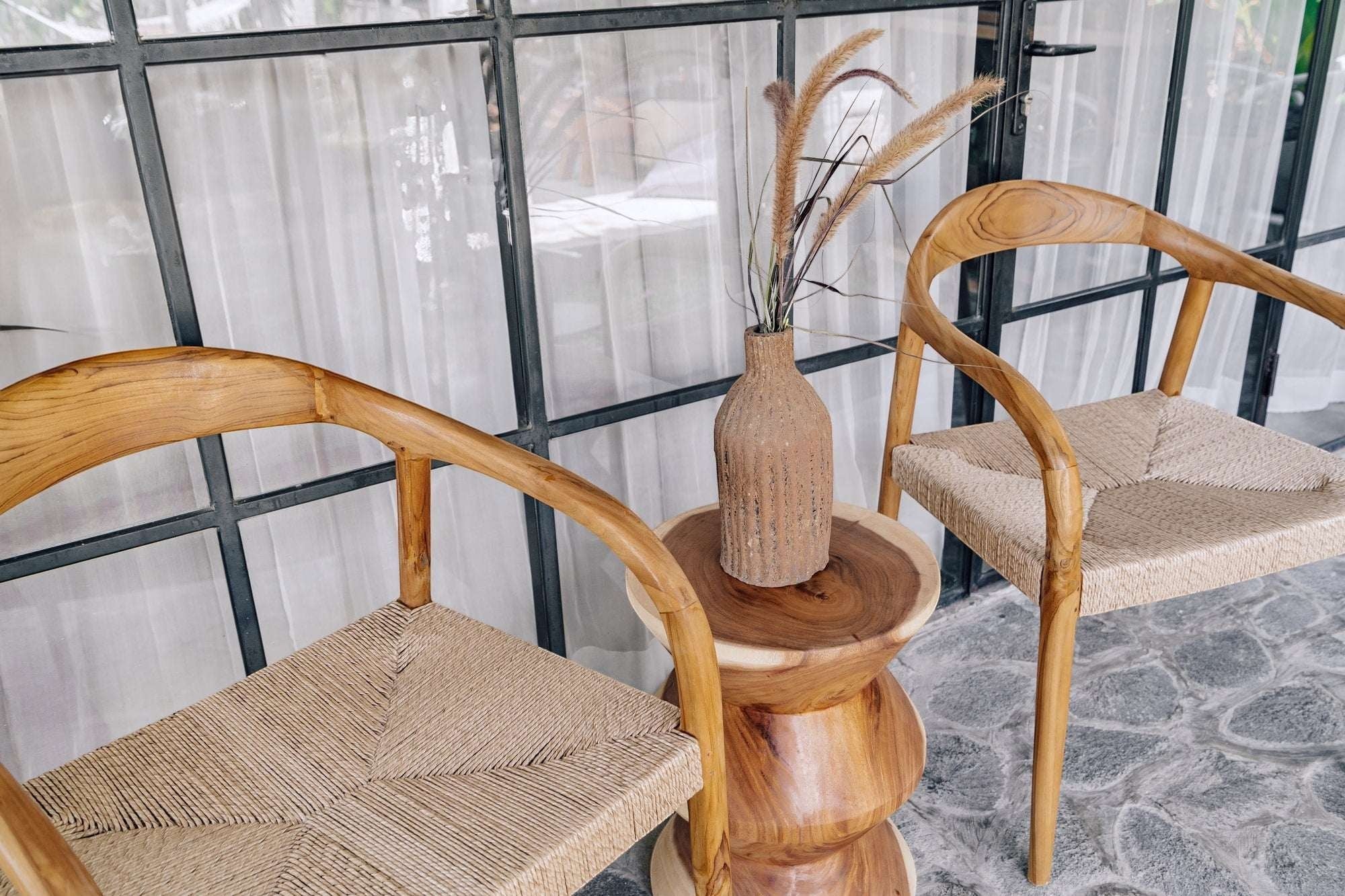 Kayu Living Cemagi chair with curved teak frame and handwoven rope seat, suitable for indoor/outdoor use.