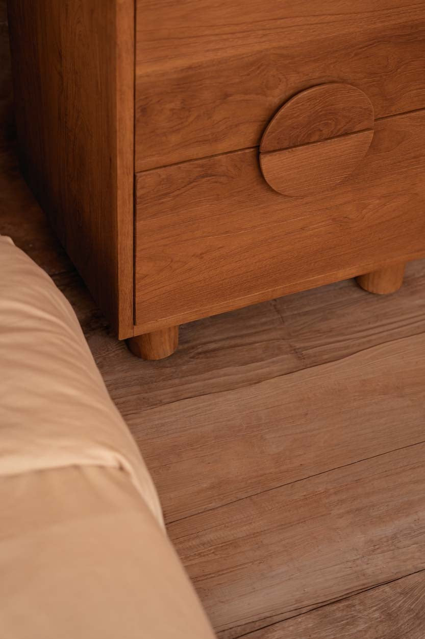 Kayu Living Eclipse nightstand in solid teak with two drawers, circular handles, and a warm natural wood grain finish.
