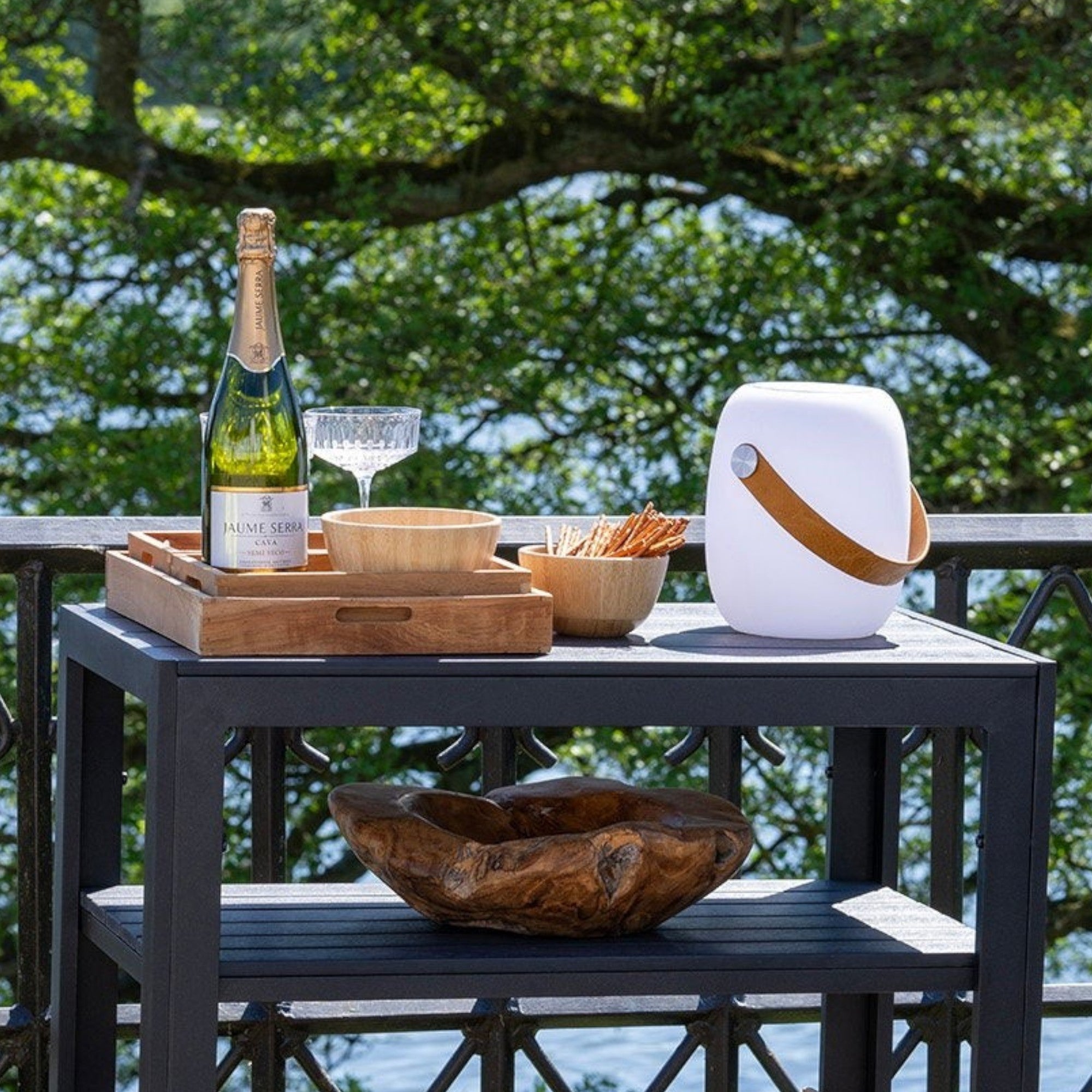 Kayu Living set of 3 natural teak serving trays with warm grain and smooth finish, on a table with champagne and snacks.