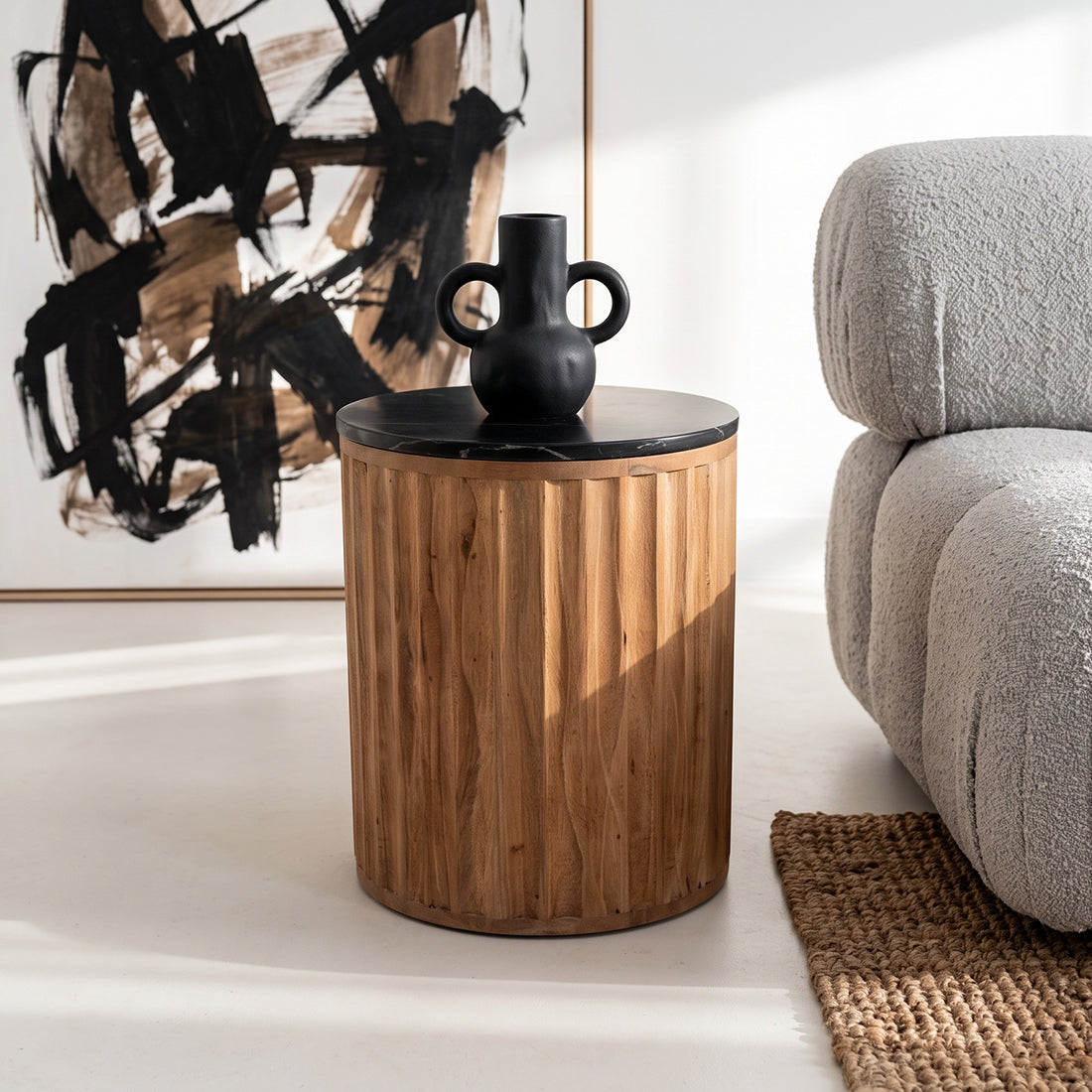 Kayu Living Langkawi side table with a black marble top and a cylindrical, fluted mango wood base in a living room.