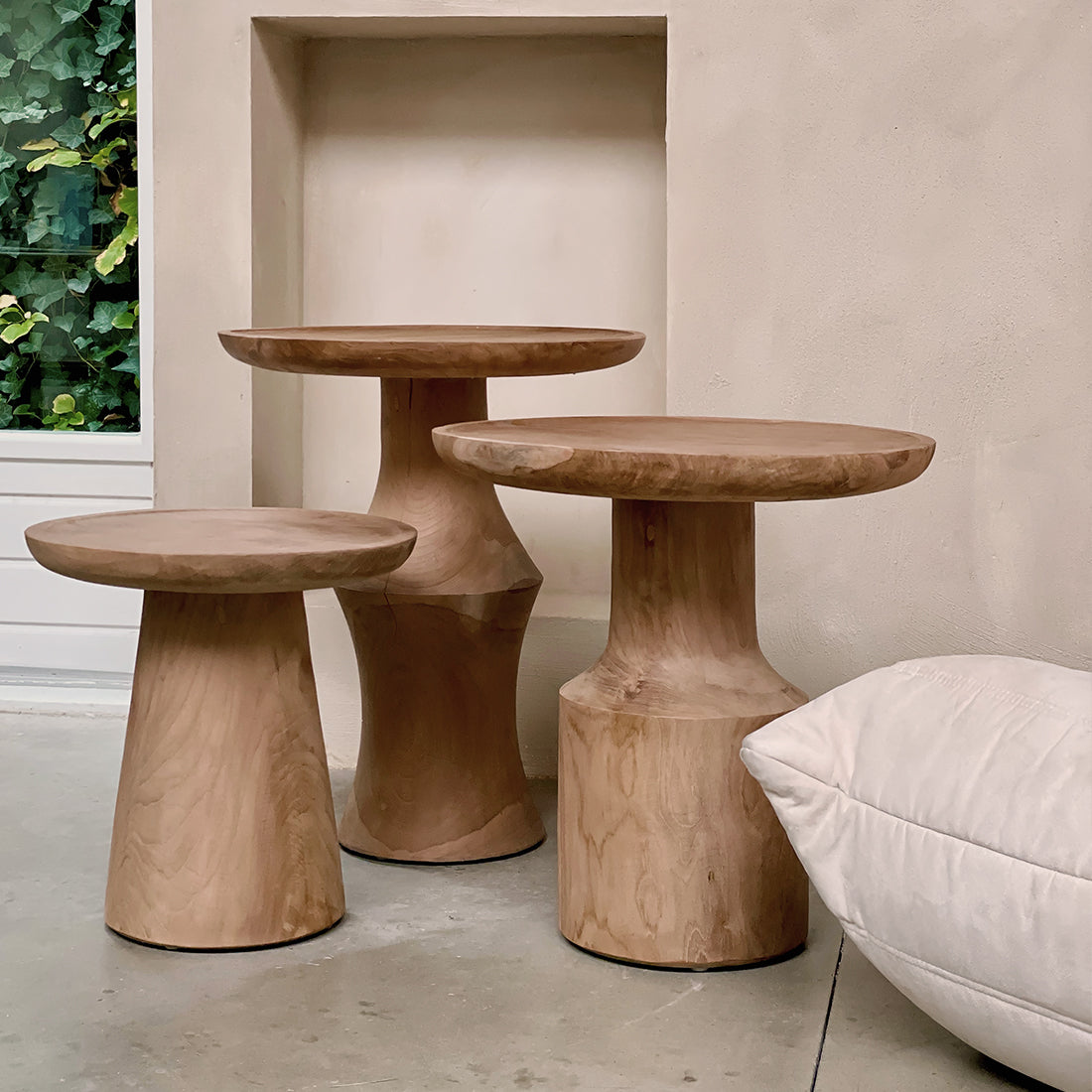 Kayu Living Nero Day teak side tables in natural wood finish with modern pedestal bases in a minimalist room.