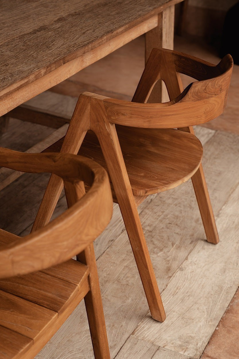 Kayu Living Nihi Oka dining chair in natural teak wood with curved back and sculpted arms, perfect for indoor or outdoor use.