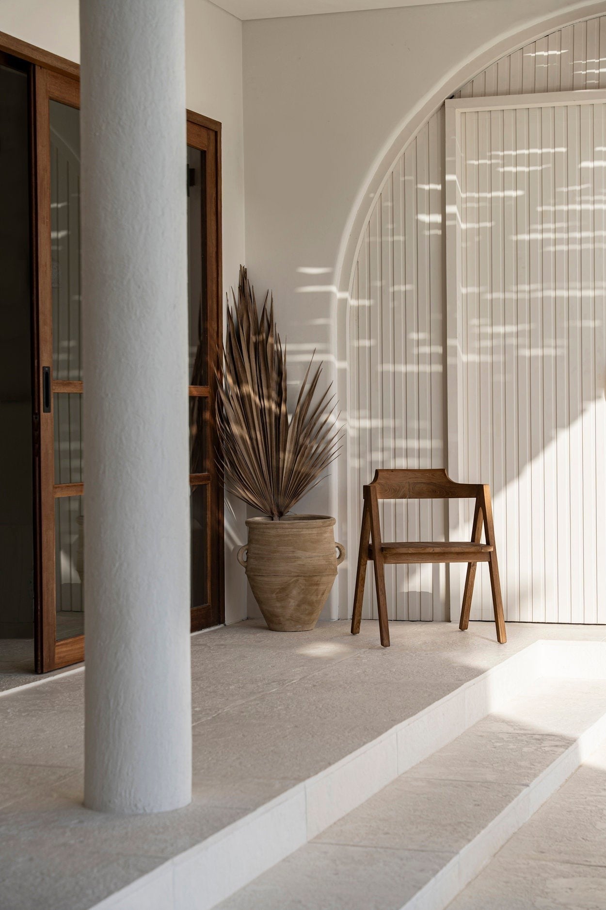 Kayu Living Nihi Sumba outdoor dining chair in natural teak with sculpted curves and crisp lines.