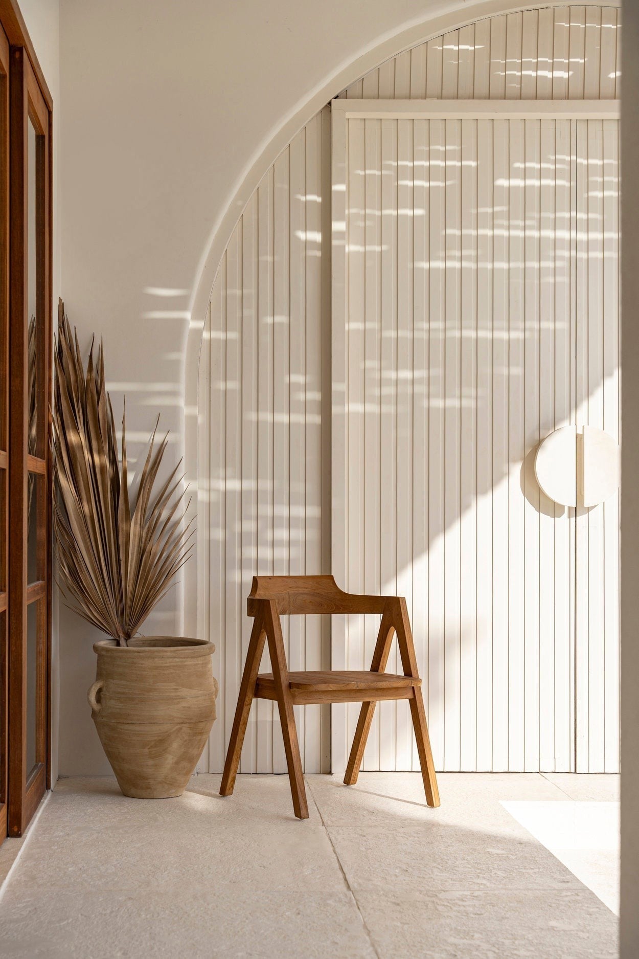 Kayu Living Nihi Sumba outdoor dining chair in natural teak with sculpted curves and crisp lines.