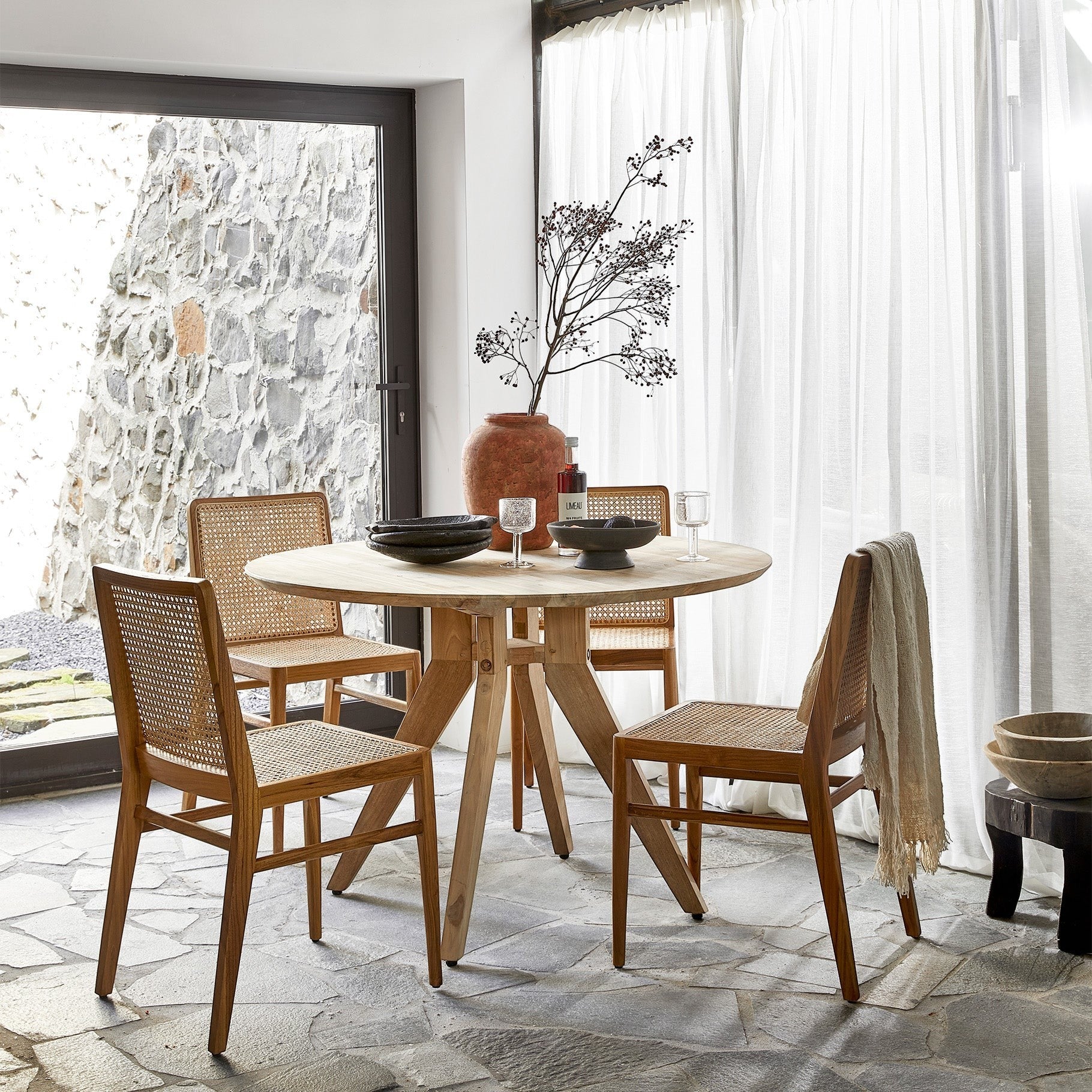 Kayu Living Nova teak dining chairs with hand-woven rattan seats and backs in a bright, modern dining room setting.