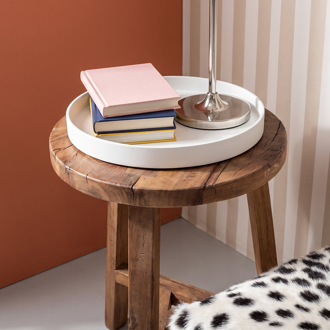 Kayu Living brown reclaimed wood stool used as a side table with a white tray, books, and lamp on top.