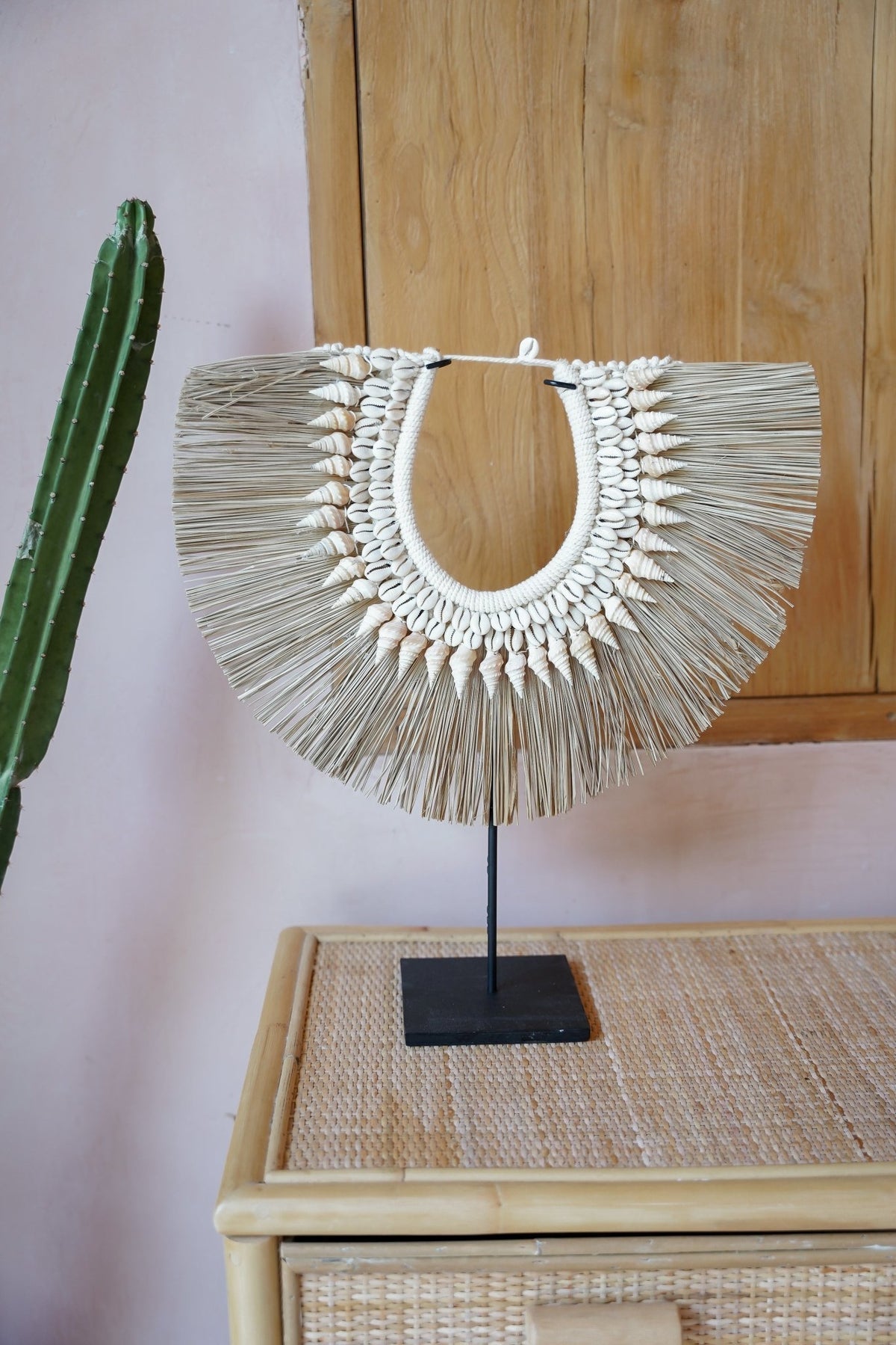 Kayu Living handmade seagrass hanger on a black stand, decorated with natural sea shells in a neutral boho style.