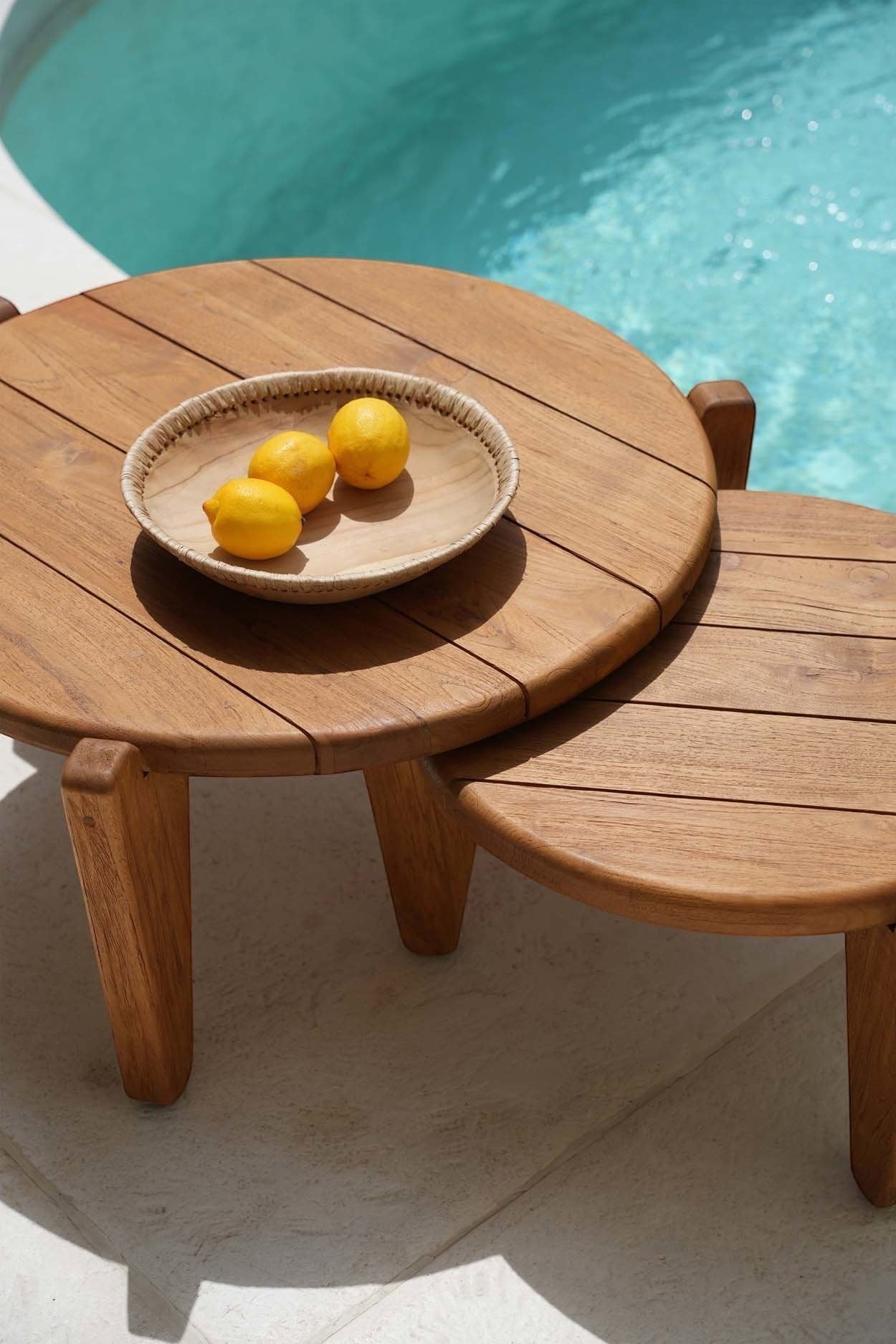 Kayu Living Seseh Coffee Table M, round reclaimed teak with three legs, next to a pool.