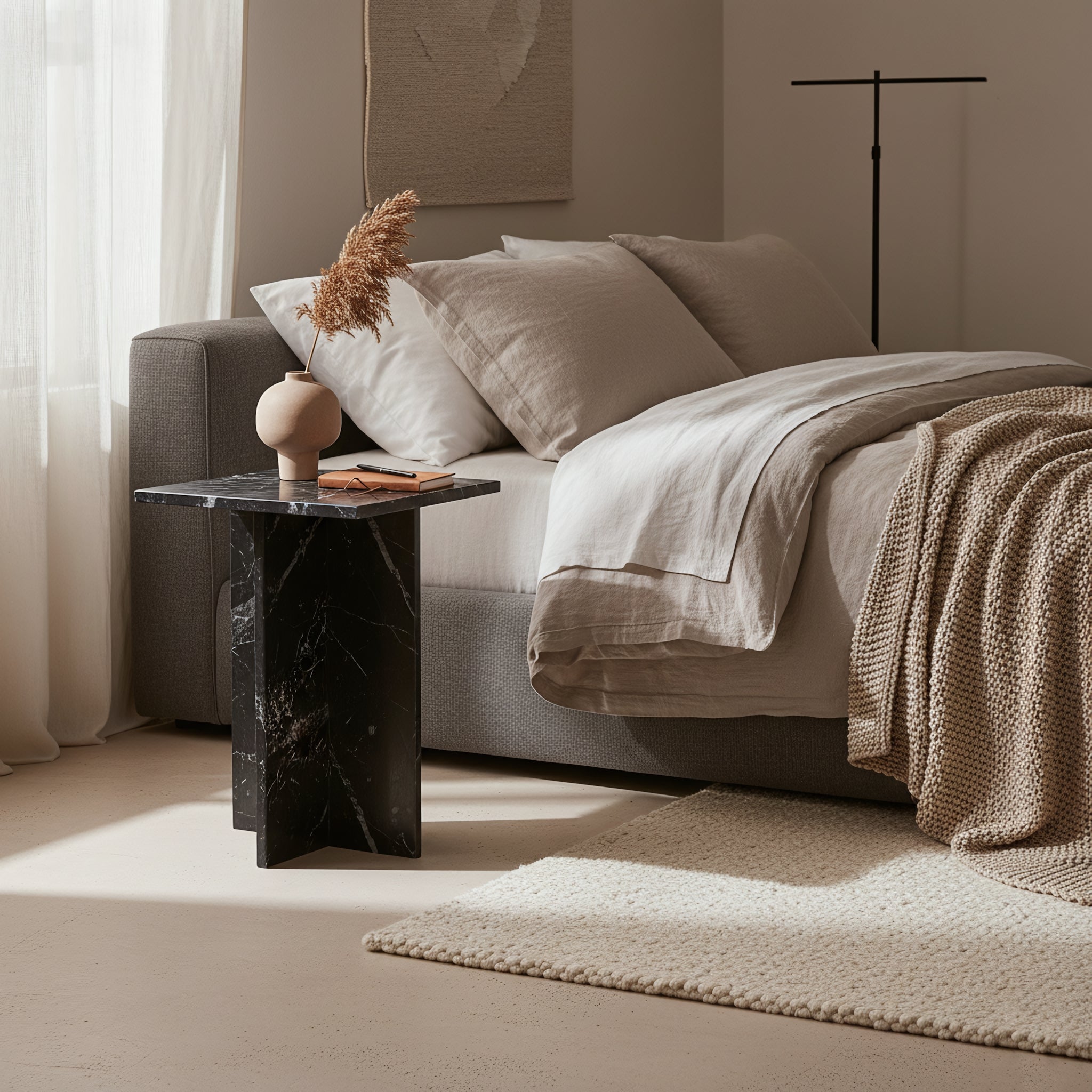 Kayu Living Shanghai black marble side table with white veining, featuring a crossed base next to a neutral bedroom.