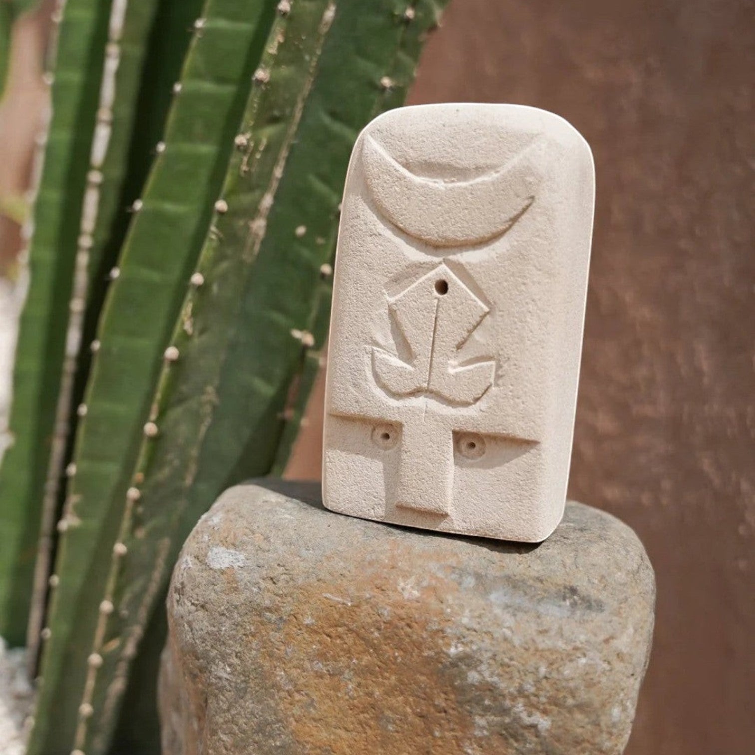 Kayu Living handmade stone guardian figurine with carved crescent and leaf symbols, natural beige finish.