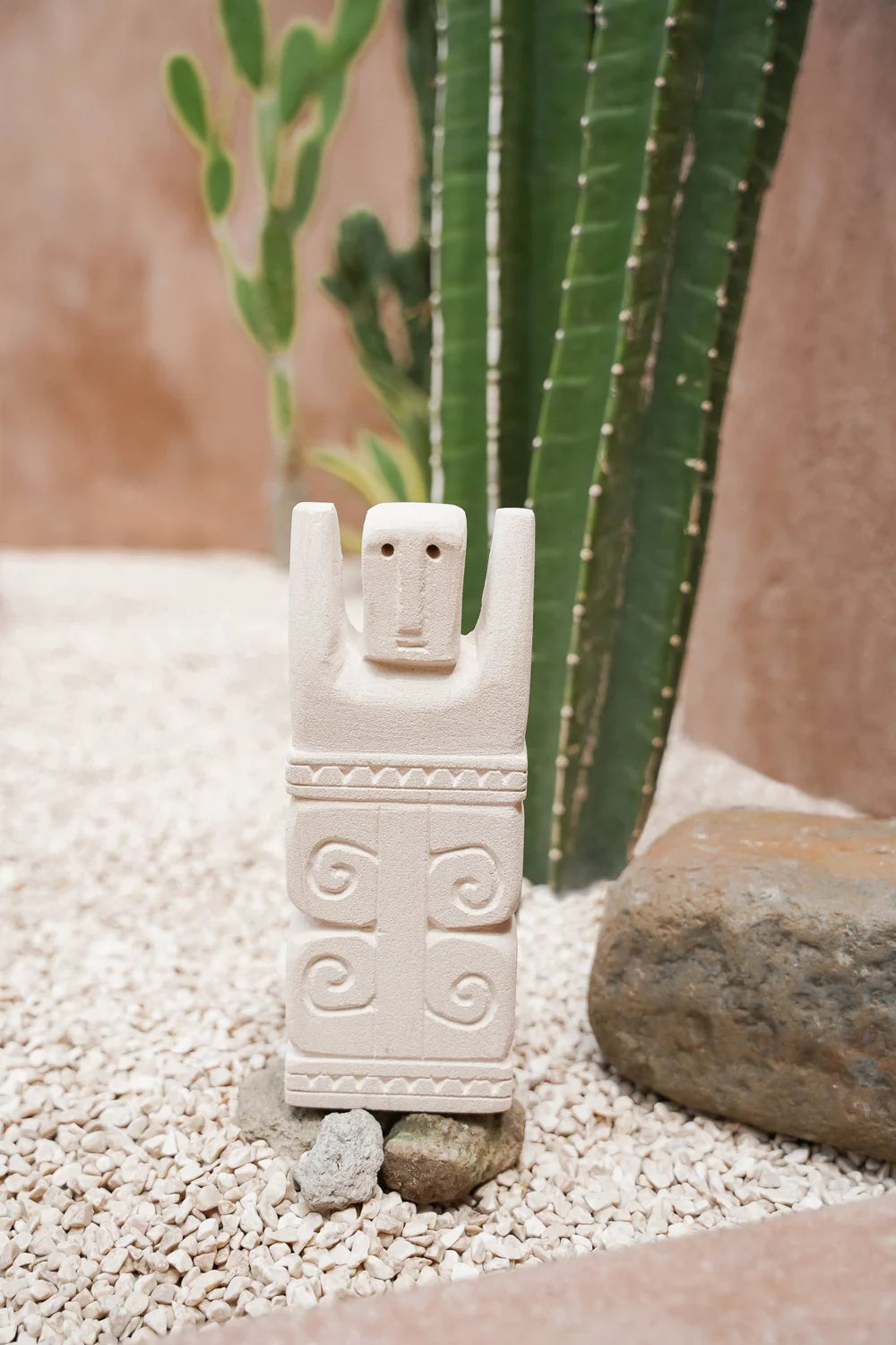 Kayu Living handcrafted Balinese stone guardian figurine with carved spiral patterns standing on white gravel
