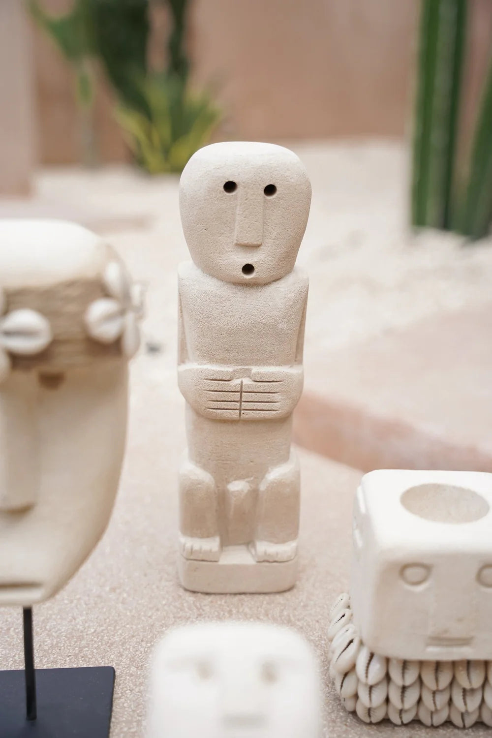 Kayu Living handcrafted beige stone figurine of a stylized guardian figure on a sandy surface