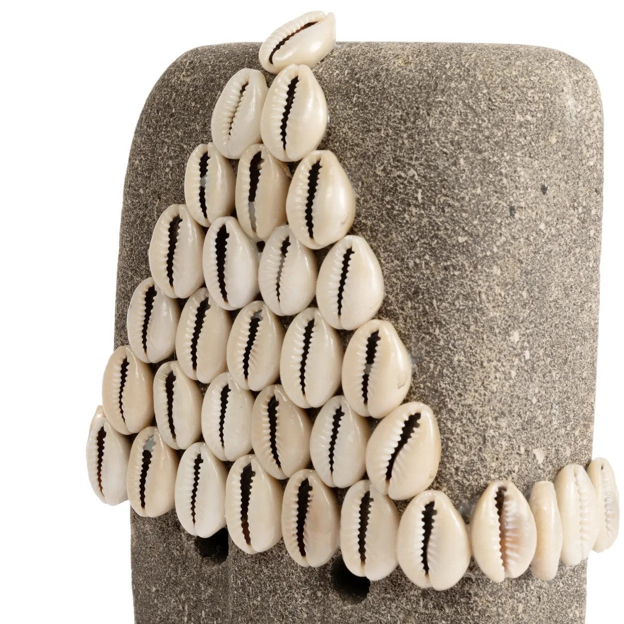 Kayu Living hand-carved grey sandstone Sumba stone statue decorated with white cowrie shells on a display stand