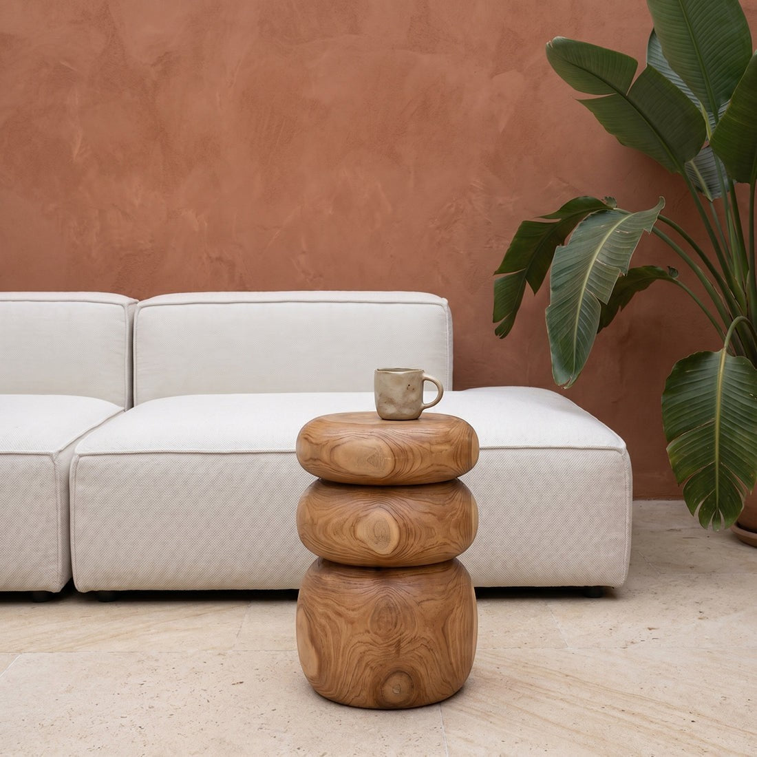 Kayu Living Tao solid teak side table with rounded, stone-like stacked design in a modern living room setting.