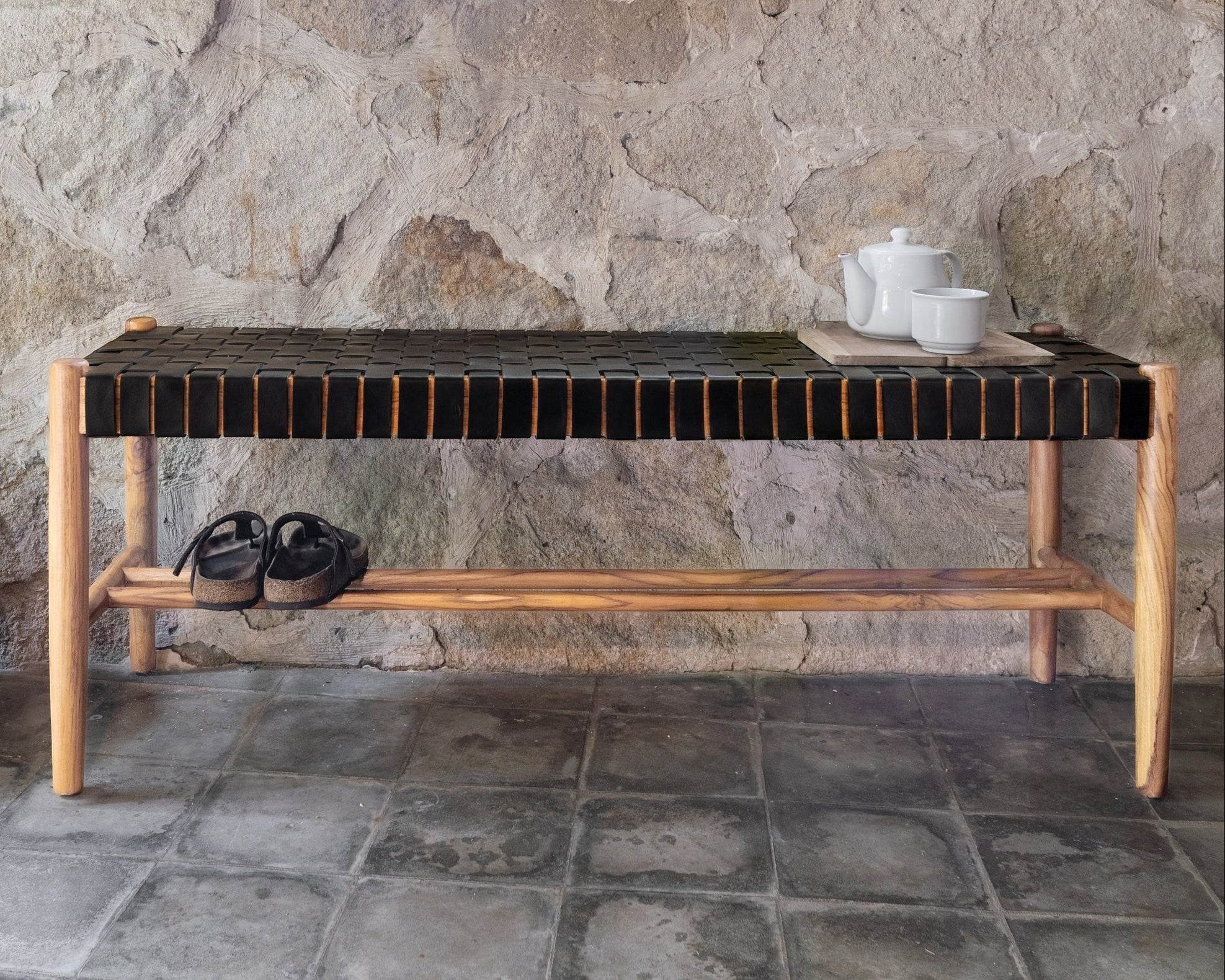 Kayu Living Umalas 120cm bench with solid teak frame and black woven leather seat, featuring a lower shelf.