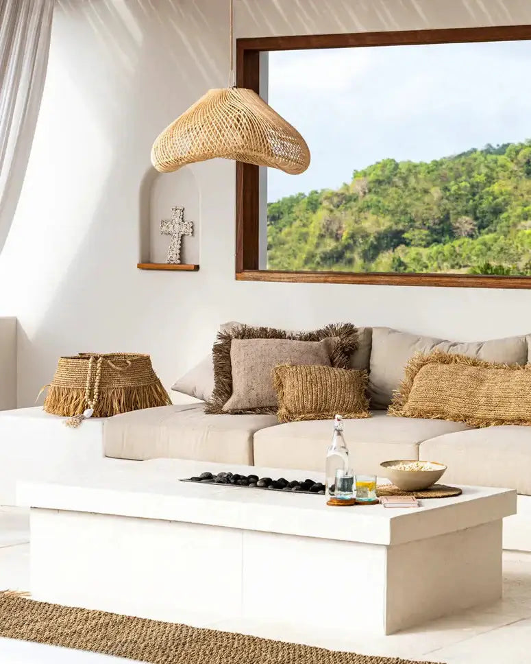 Modern living room with a white sofa, wooden armchair, and large windows overlooking greenery.