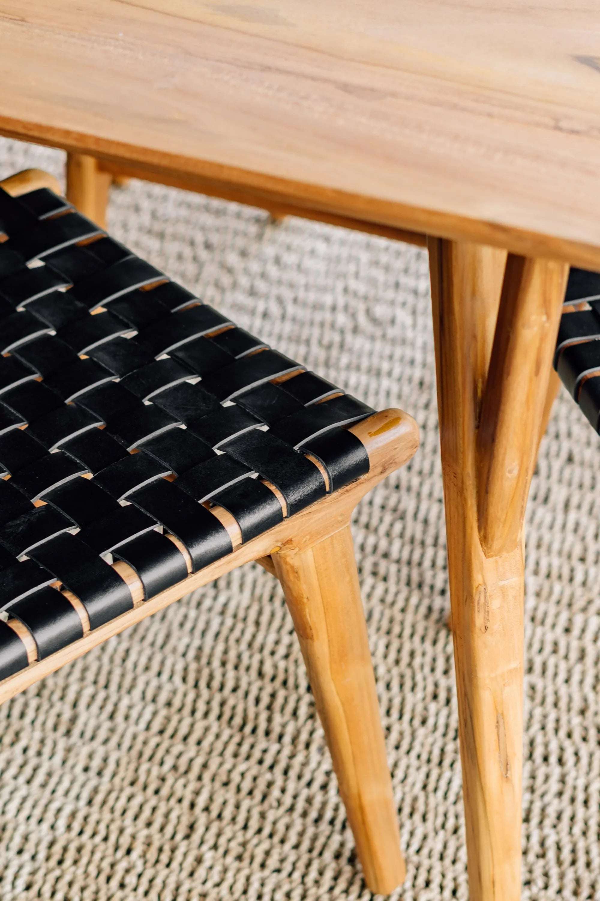 Handcrafted wooden table and woven black leather chair on textured rug, Kayu Living furniture