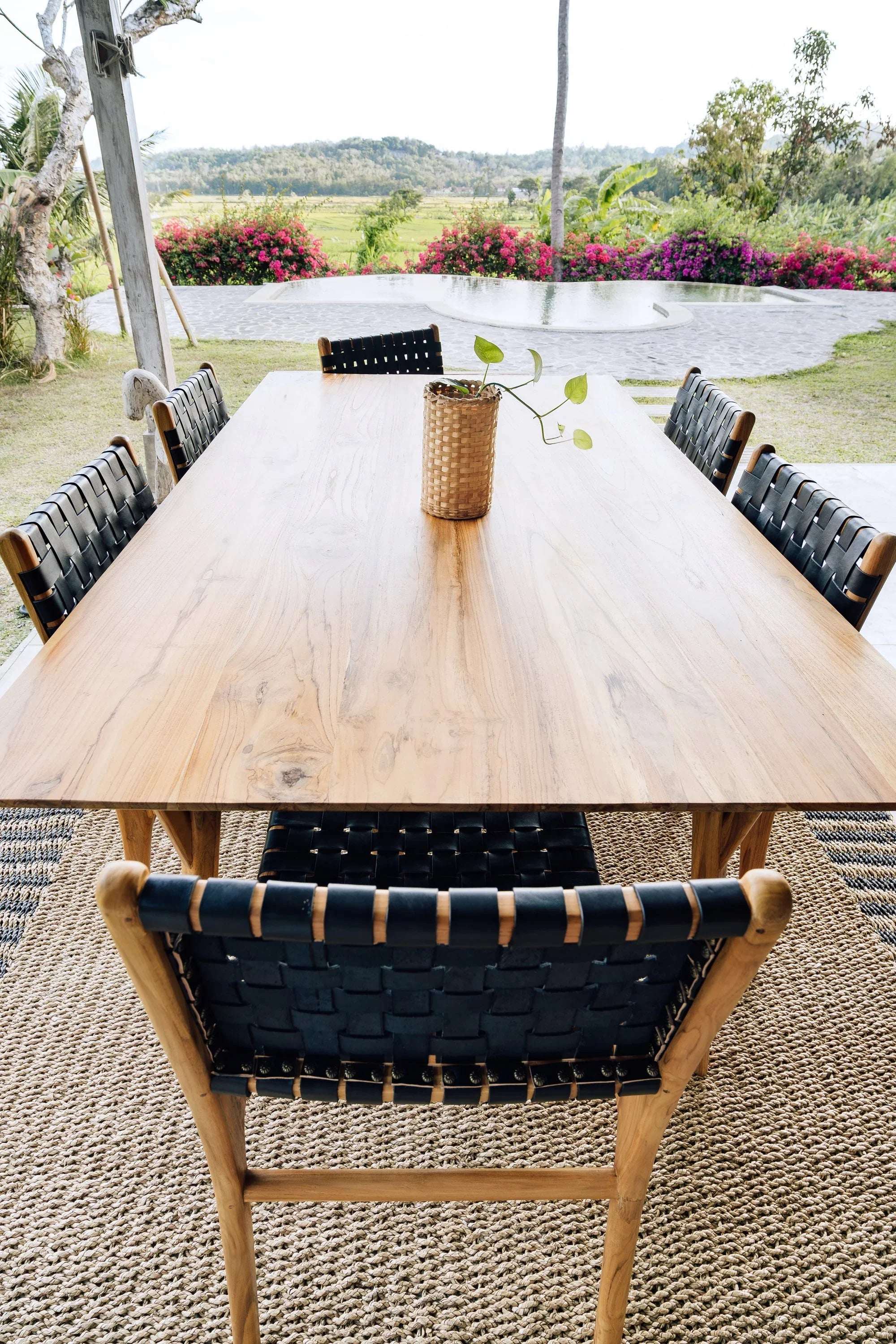 Handcrafted wooden dining table with woven chairs by Kayu Living, outdoor setting, nature view