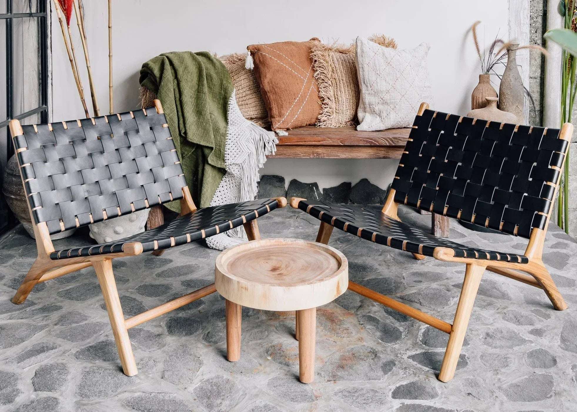 Handcrafted lounge chairs with woven black seats and a wooden table, styled with natural decor by Kayu Living.