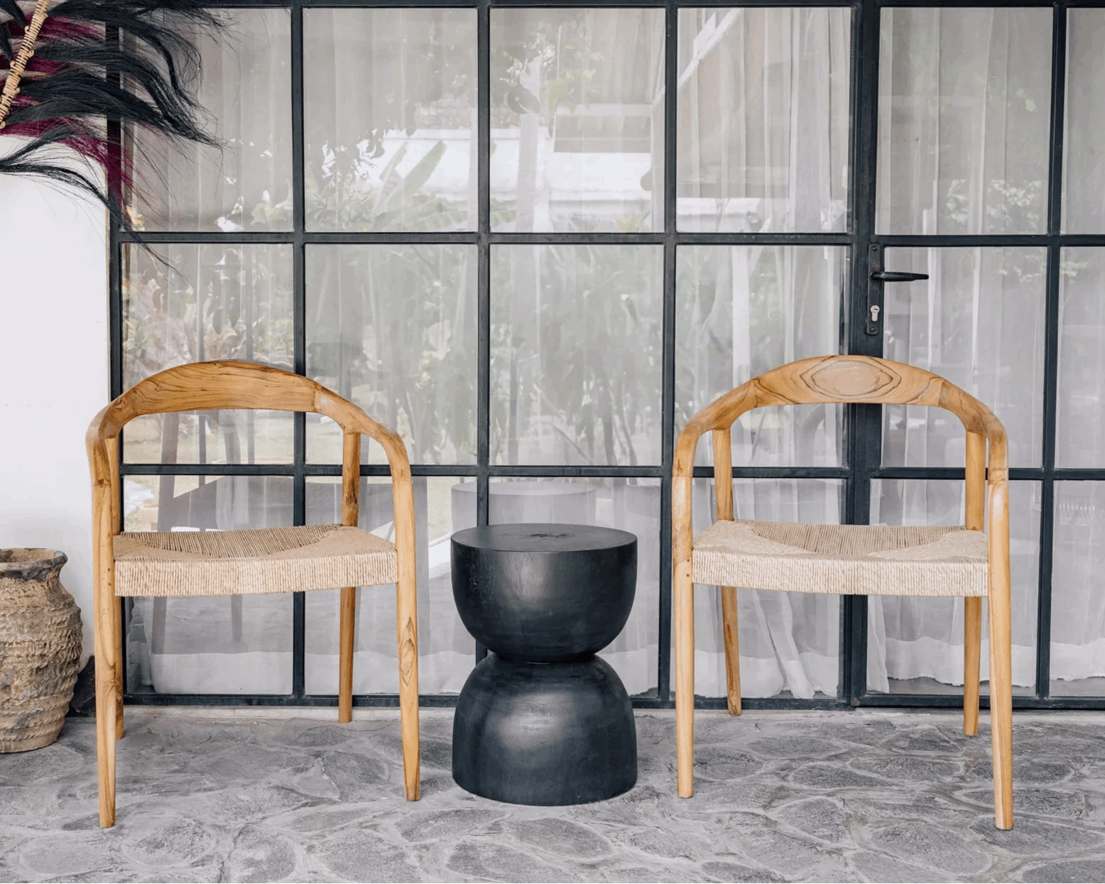 Two handcrafted wooden chairs with woven seats and a black side table by Kayu Living