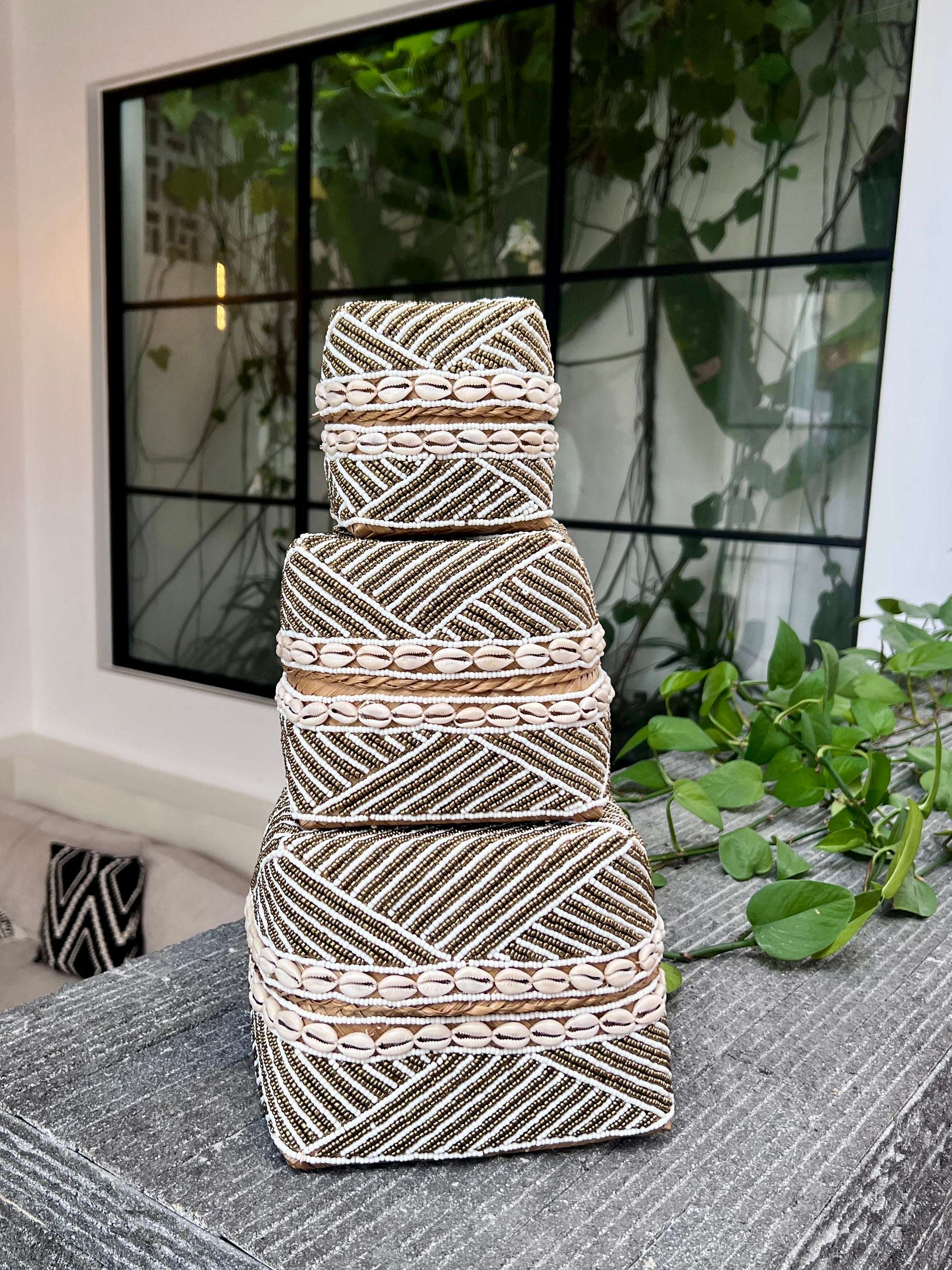 Stack of decorative woven baskets on a textured surface with a blurred indoor background