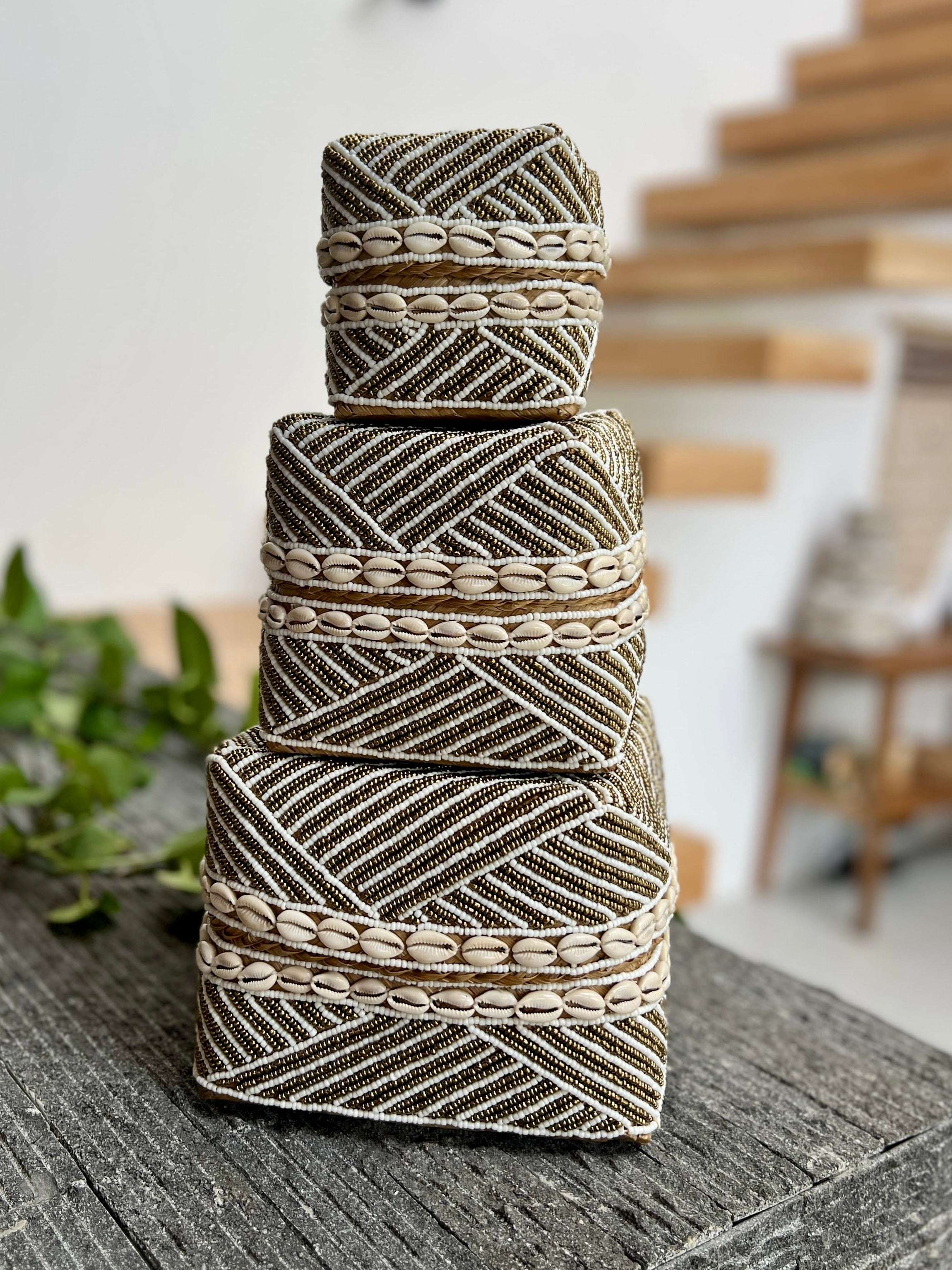 Stack of decorative woven boxes on a wooden surface with a blurred indoor background