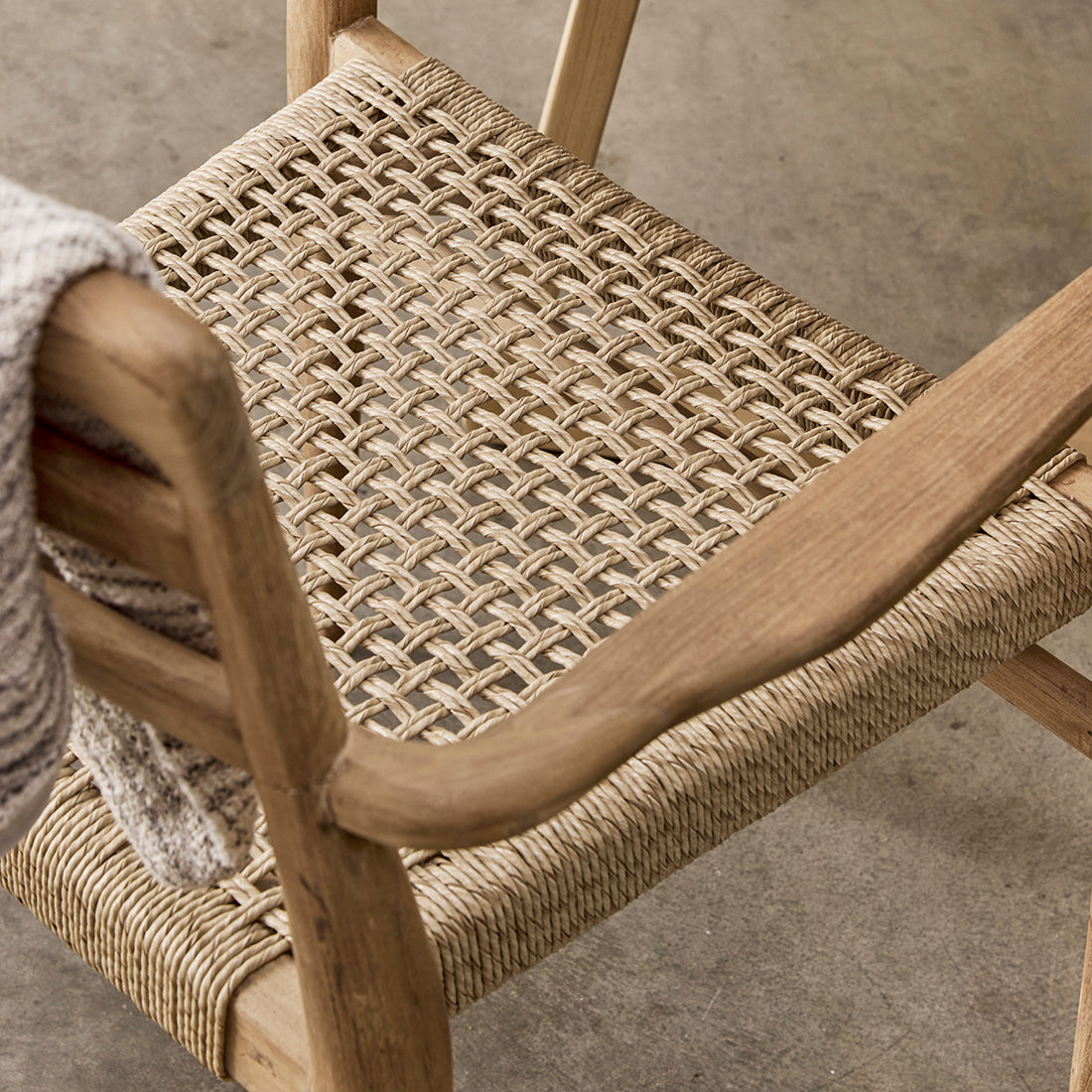 Set of two Raw Materials Verano teak dining chairs with armrests, showcasing sleek design and smooth teak wood finish.