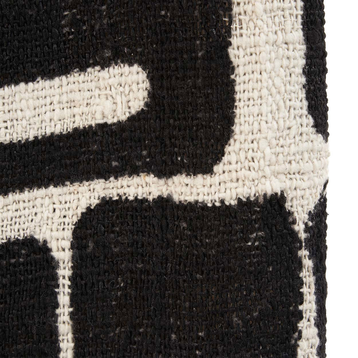 Close-up of a Kayu Living woven cotton bed throw featuring a bold black and natural white Aztec geometric pattern.