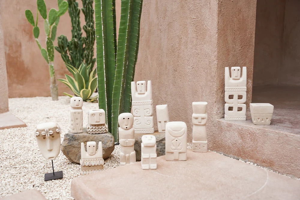 Kayu Living handcrafted Balinese stone guardian figurines in various shapes displayed on a gravel patio with cacti
