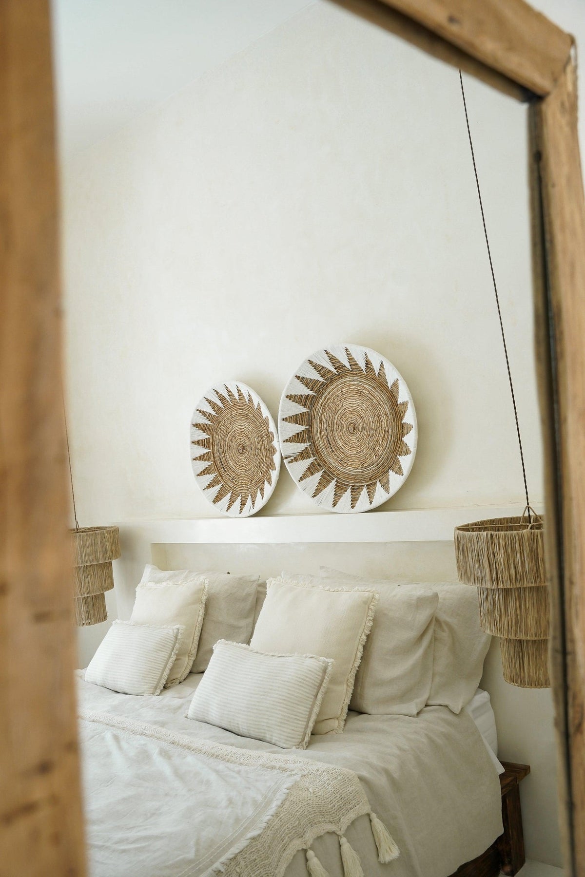 Kayu Living handcrafted bamboo star wall plates in white and brown displayed above a bohemian bedroom headboard.