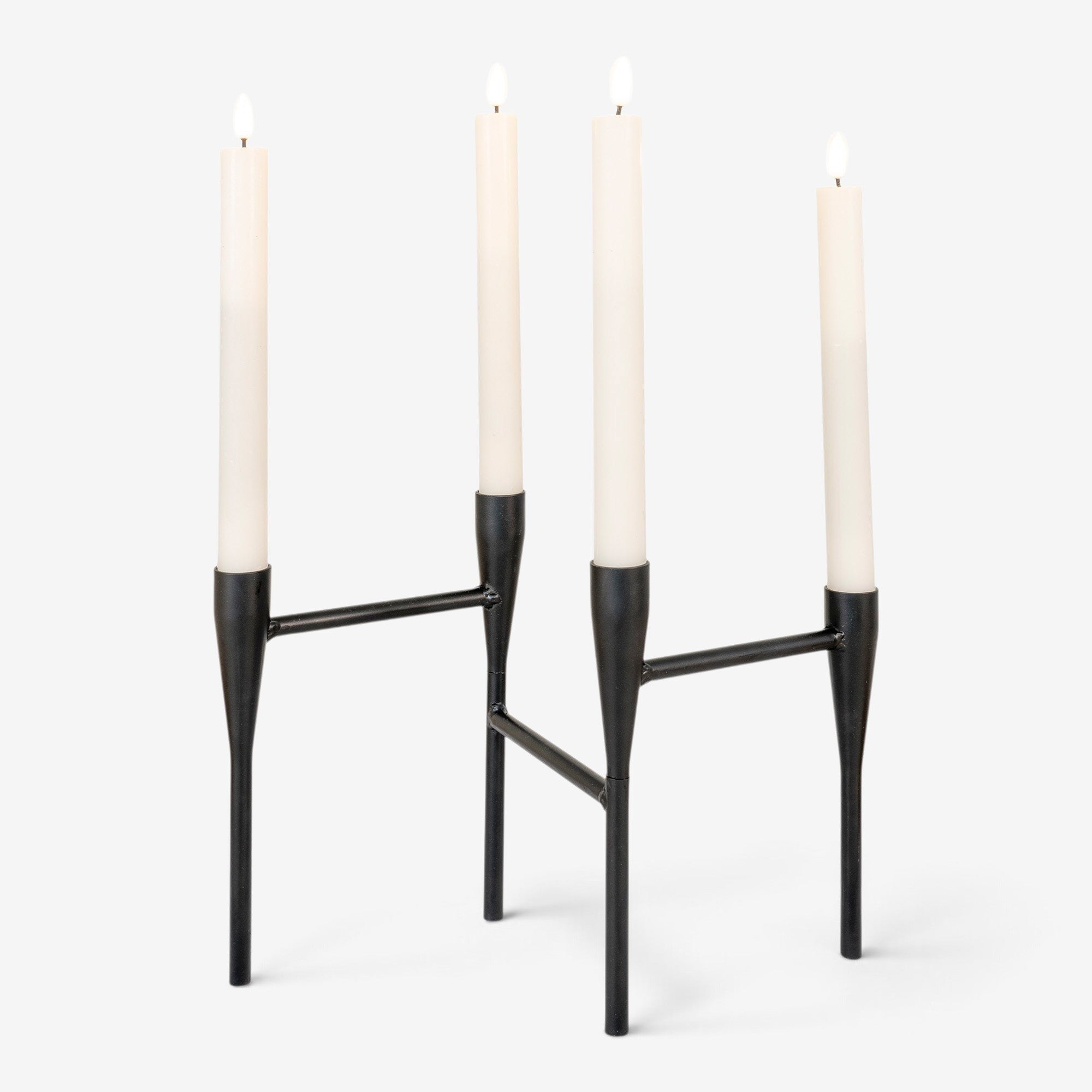 Kayu Living minimalist black steel candle holder with four tapered white candles on a white background