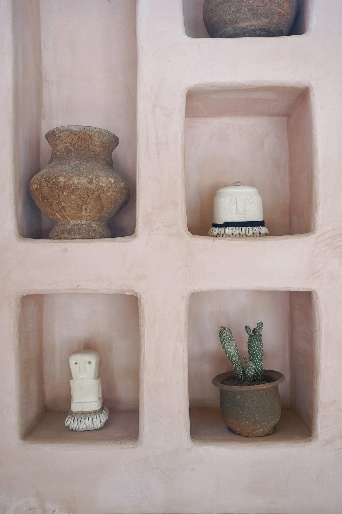 Kayu Living handmade Boho Stone Men No. 5 figurine with shell accents displayed in a pink plaster wall niche