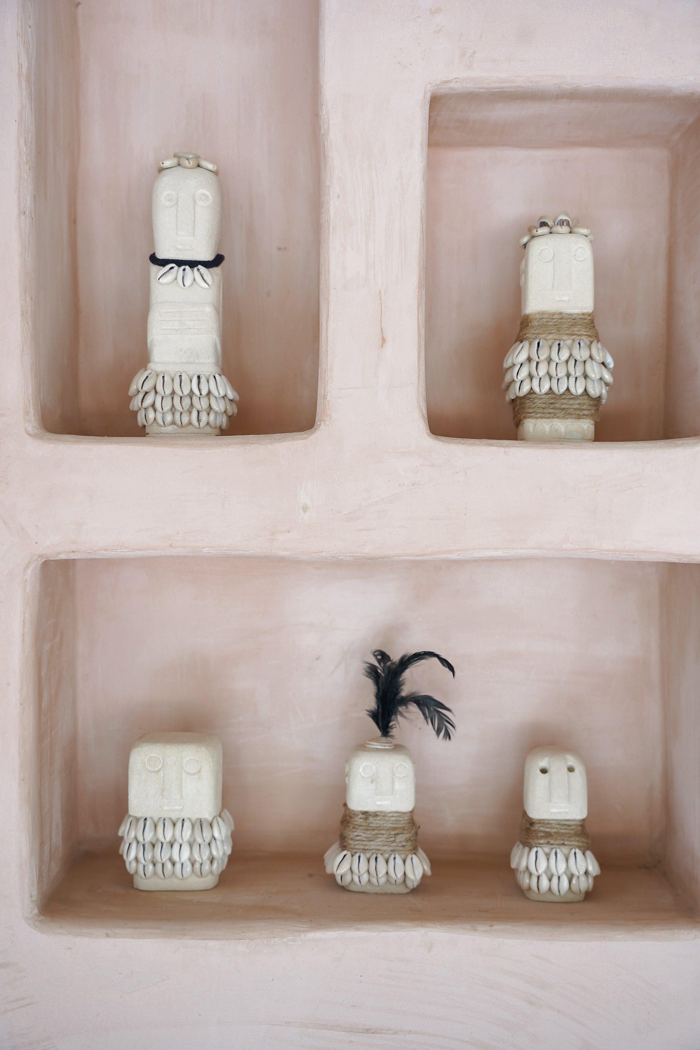Kayu Living handmade boho stone figurines decorated with shells and feathers displayed in a pink wall niche