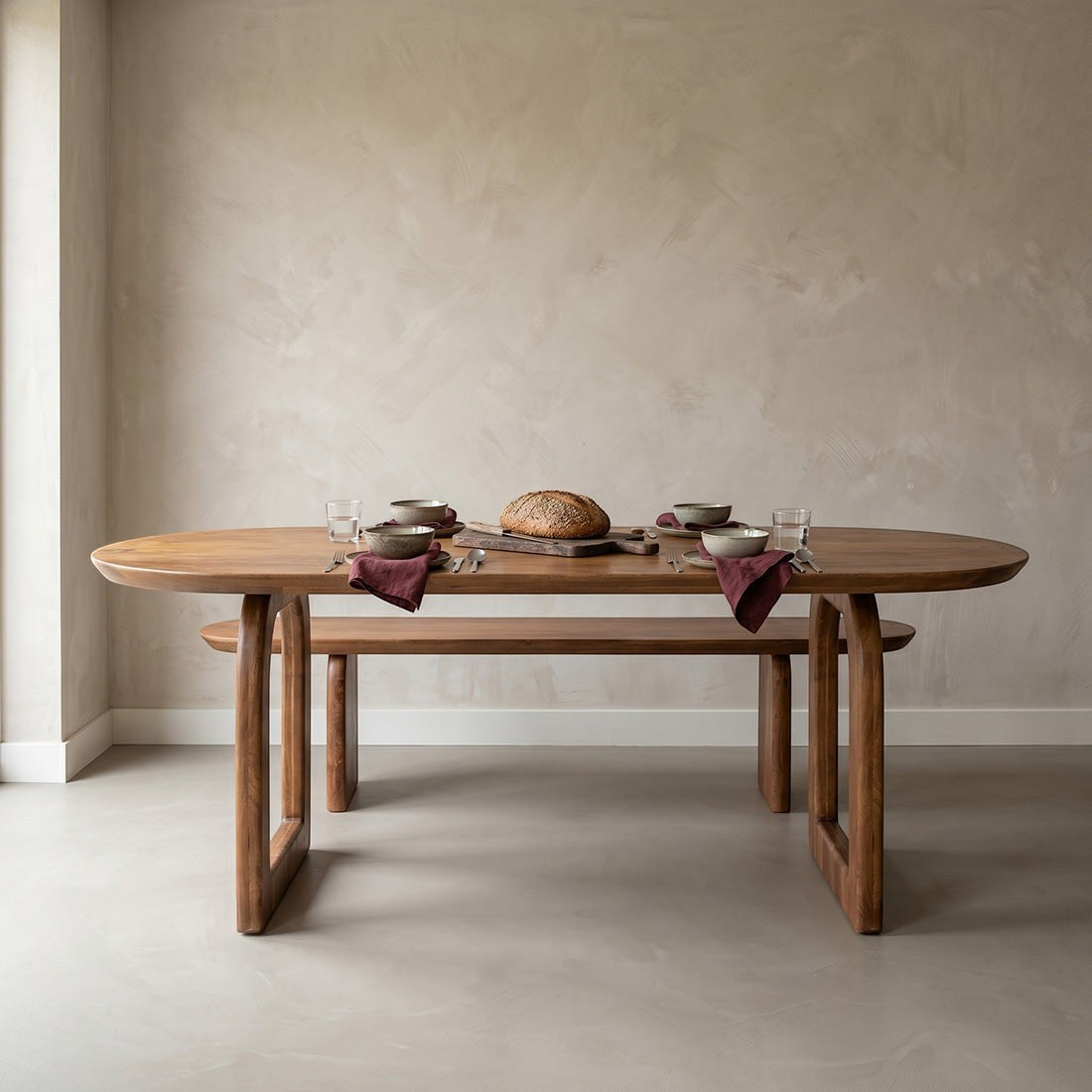 Kayu Living bullnose dining table in natural mango wood with an oval top and open base in a minimalist dining room.